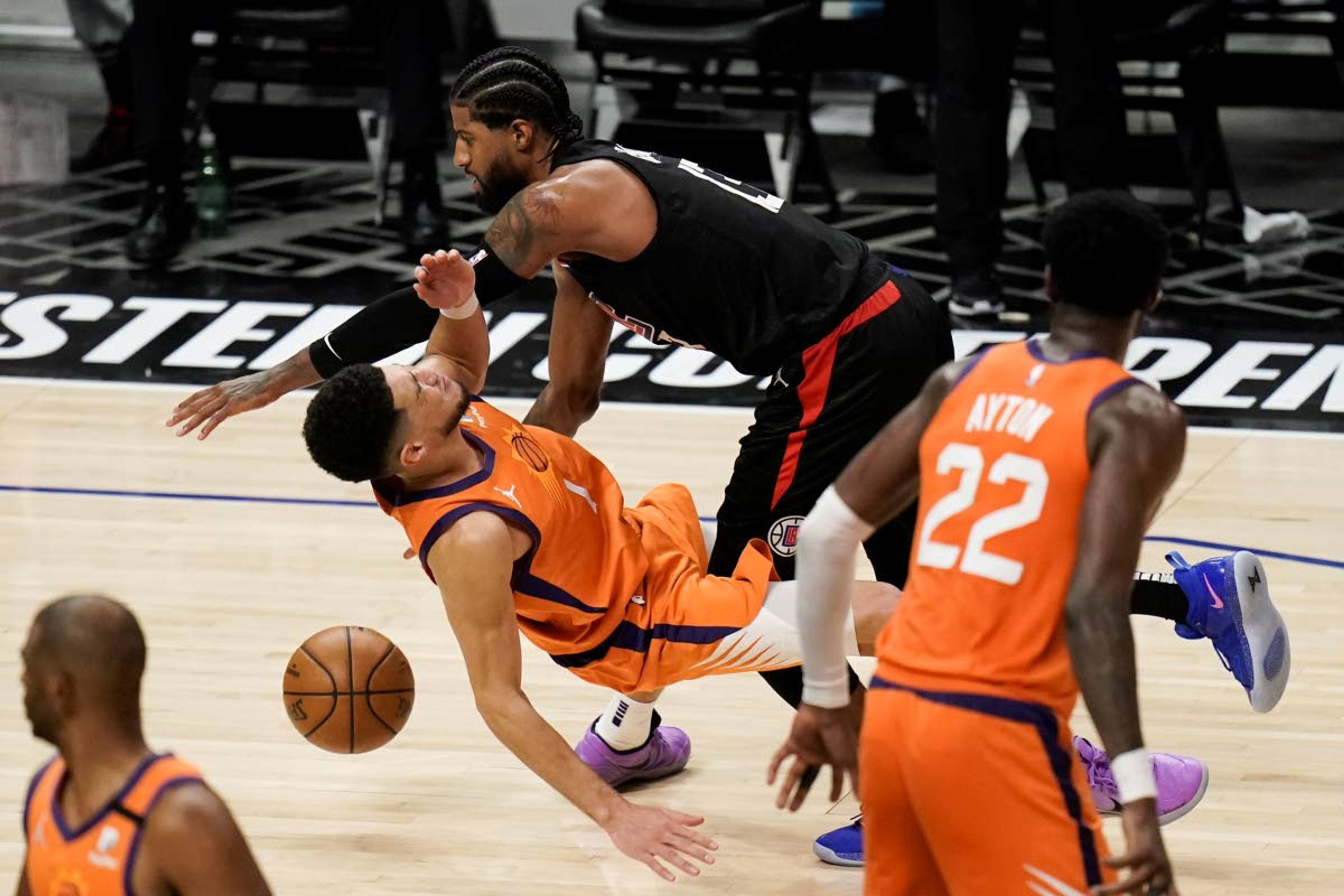 Los Angeles Clippers guard Paul George, top, fouls Phoenix Suns' Devin Booker during the second half in Game 6 of the NBA basketball Western Conference Finals Wednesday, June 30, 2021, in Los Angeles. (AP Photo/Jae C. Hong)