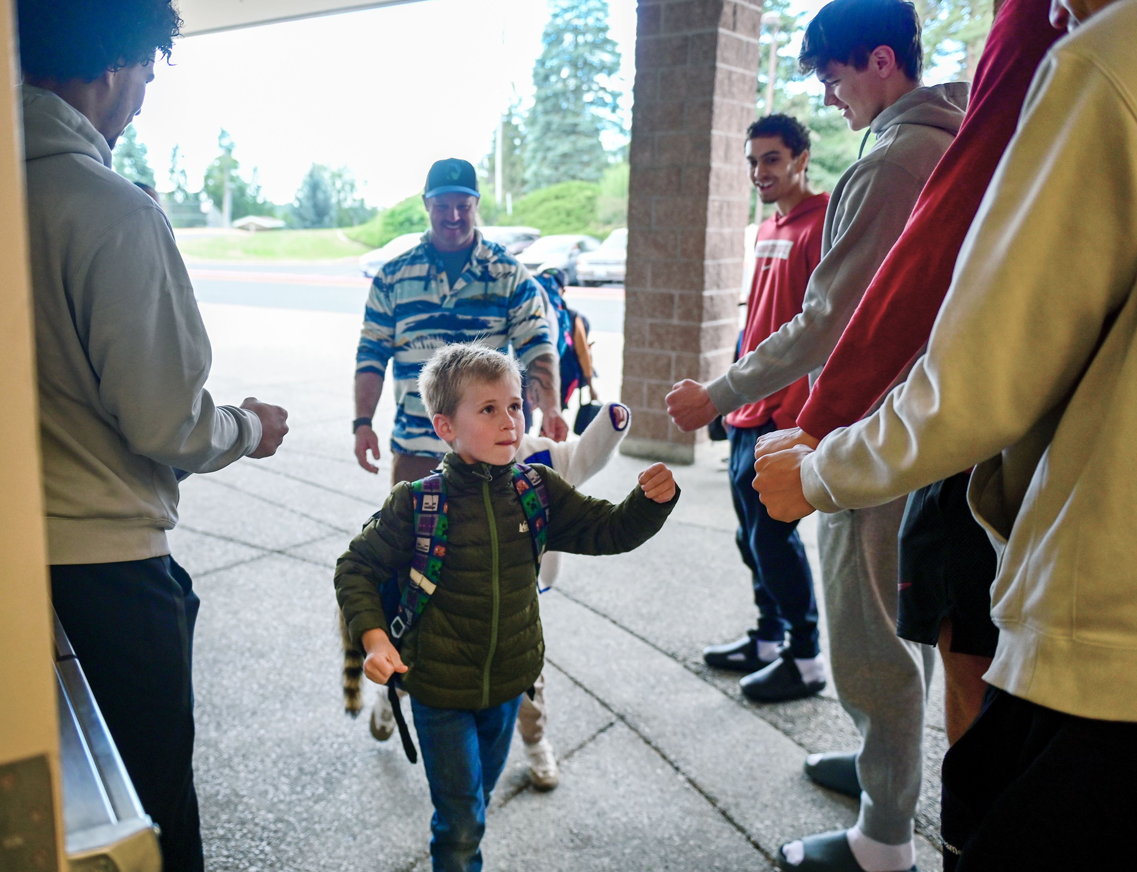 Sebastian, center, 9, fist bumps with members of the Washington State University basketball team on the way into the first day of third grade at Jefferson Elementary School on Wednesday in Pullman.