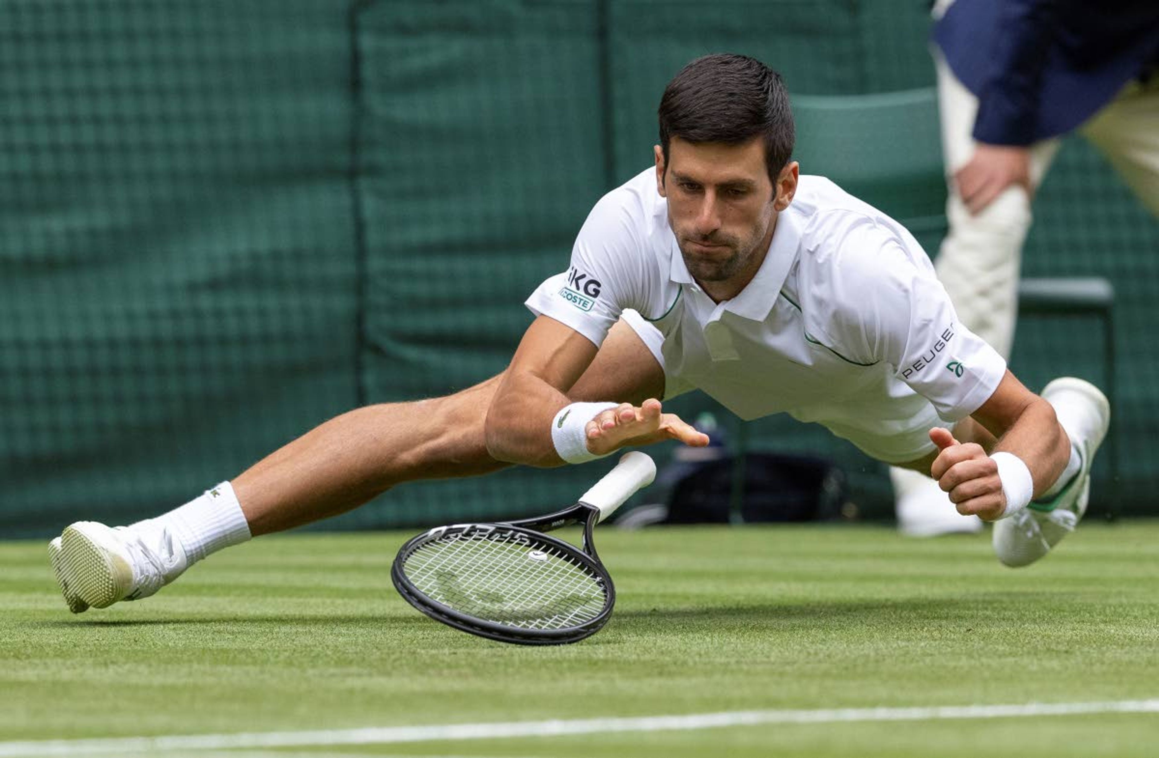 Novak Djokovic of Serbia falls whilst playing against South Africa's Kevin Anderson during the men's singles second round match on day three of the Wimbledon Tennis Championships in London, Wednesday June 30, 2021. (Ian Walton/Pool via AP)