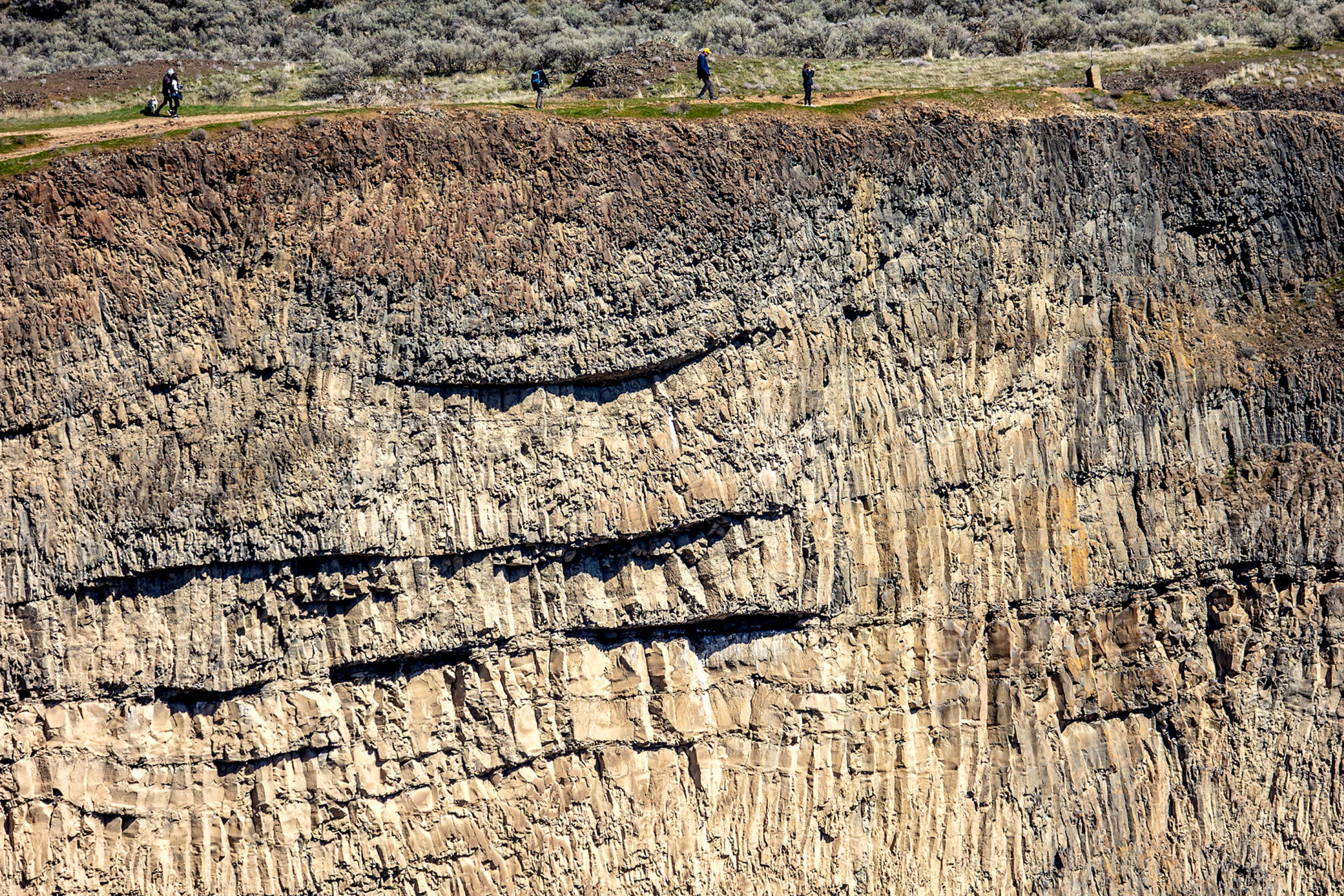 People walk along a trail leading toward the top view of Palouse Falls.