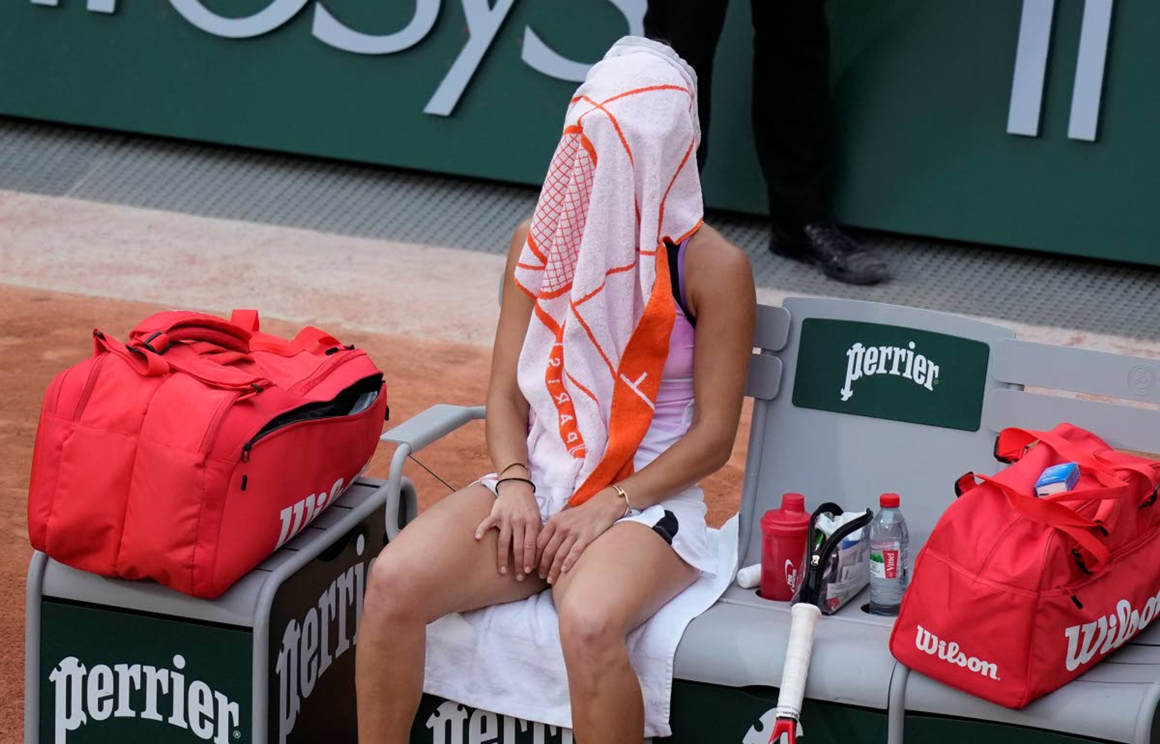 Romania's Mihaela Buzarnescu sits under her towel during a change of ends as she plays against United States Serena Williams during their second round match on day four of the French Open tennis tournament at Roland Garros in Paris, France, Wednesday, June 2, 2021. (AP Photo/Thibault Camus)