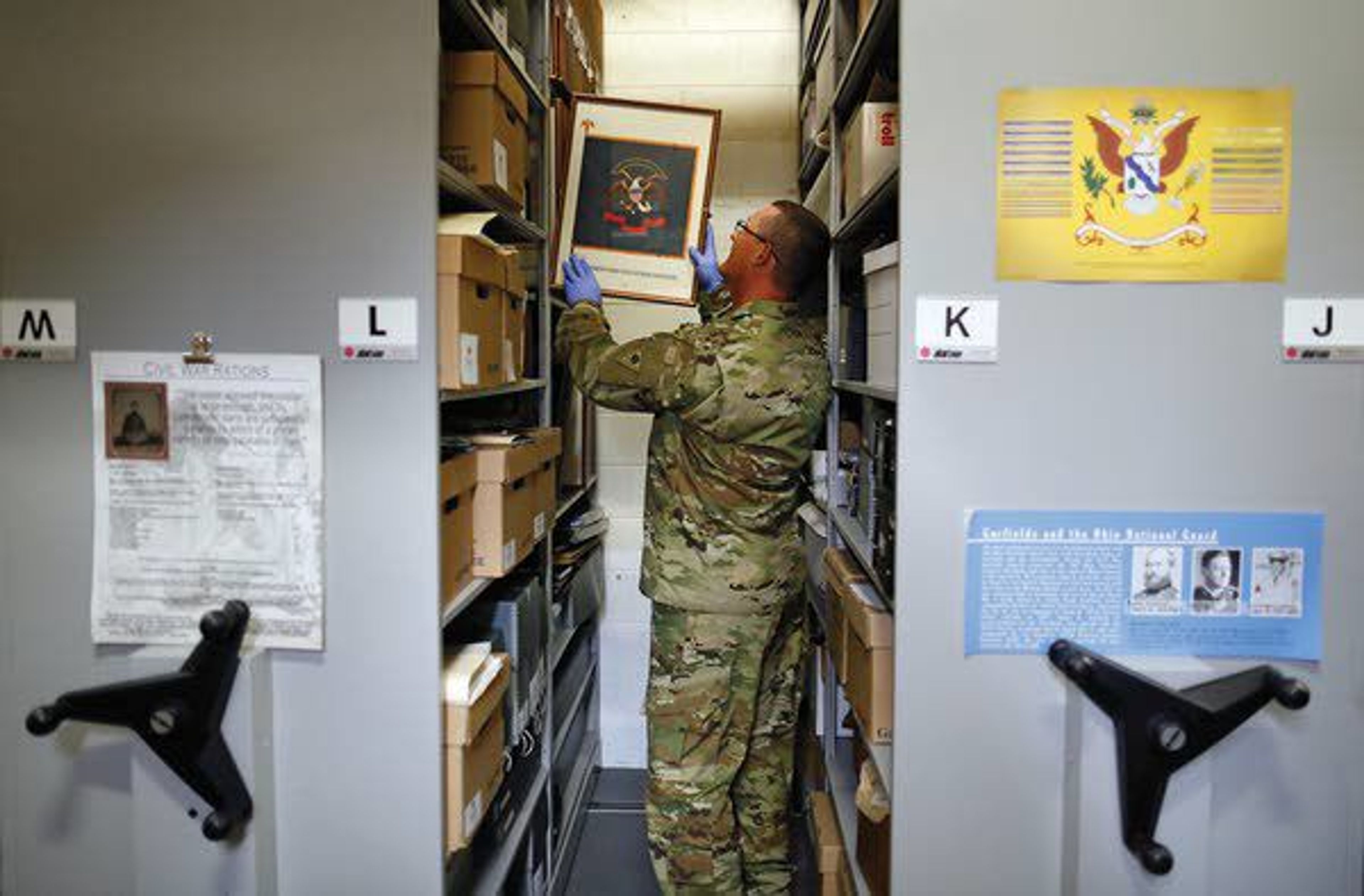 Sgt. 1st Class Josh Mann, Ohio Army National Guard historian, files away an artist’s rendering of an infantry battle flag inside the Beightler Armory on July 17 in Columbus, Ohio.