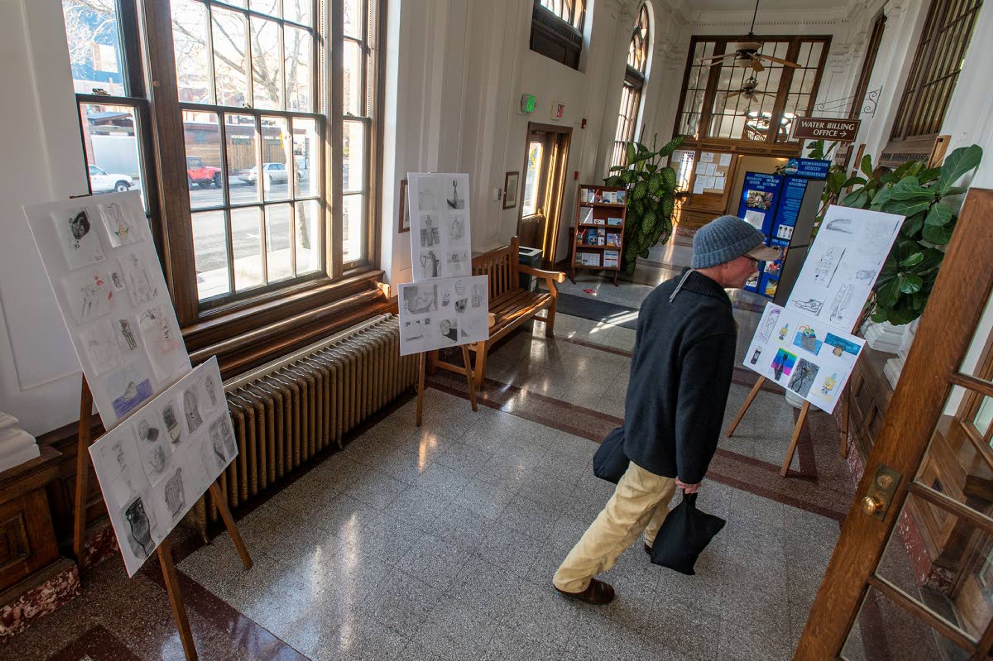 A man walks by upcycled artwork made by Moscow Middle School students at the Third Street Gallery on Friday afternoon.