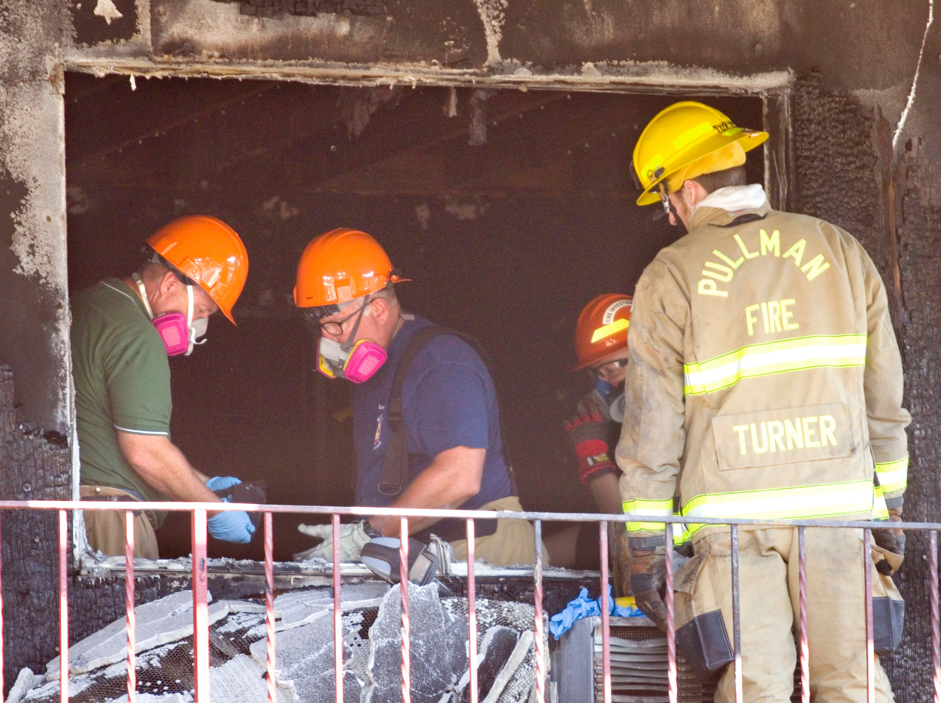 Fire Investigators work inside a room where a fire started at the American Travel Inn on Tuesday on south Grand Avenue in Pullman.