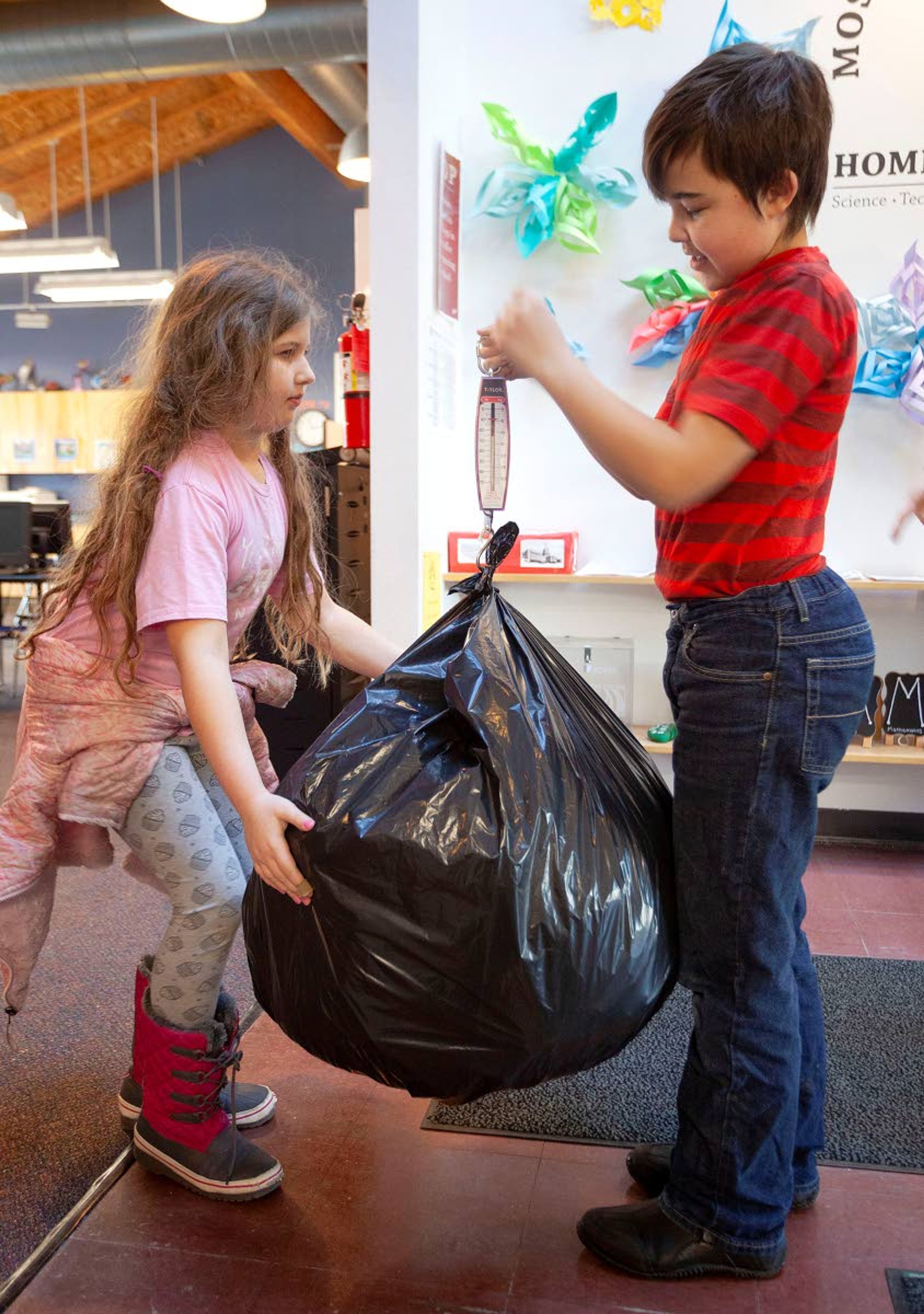 Moscow Charter School fourth-graders Meredith Johnson and Ian Mitton weigh some of the plastic bags that have been donated to their recycling program Tuesday in Moscow.