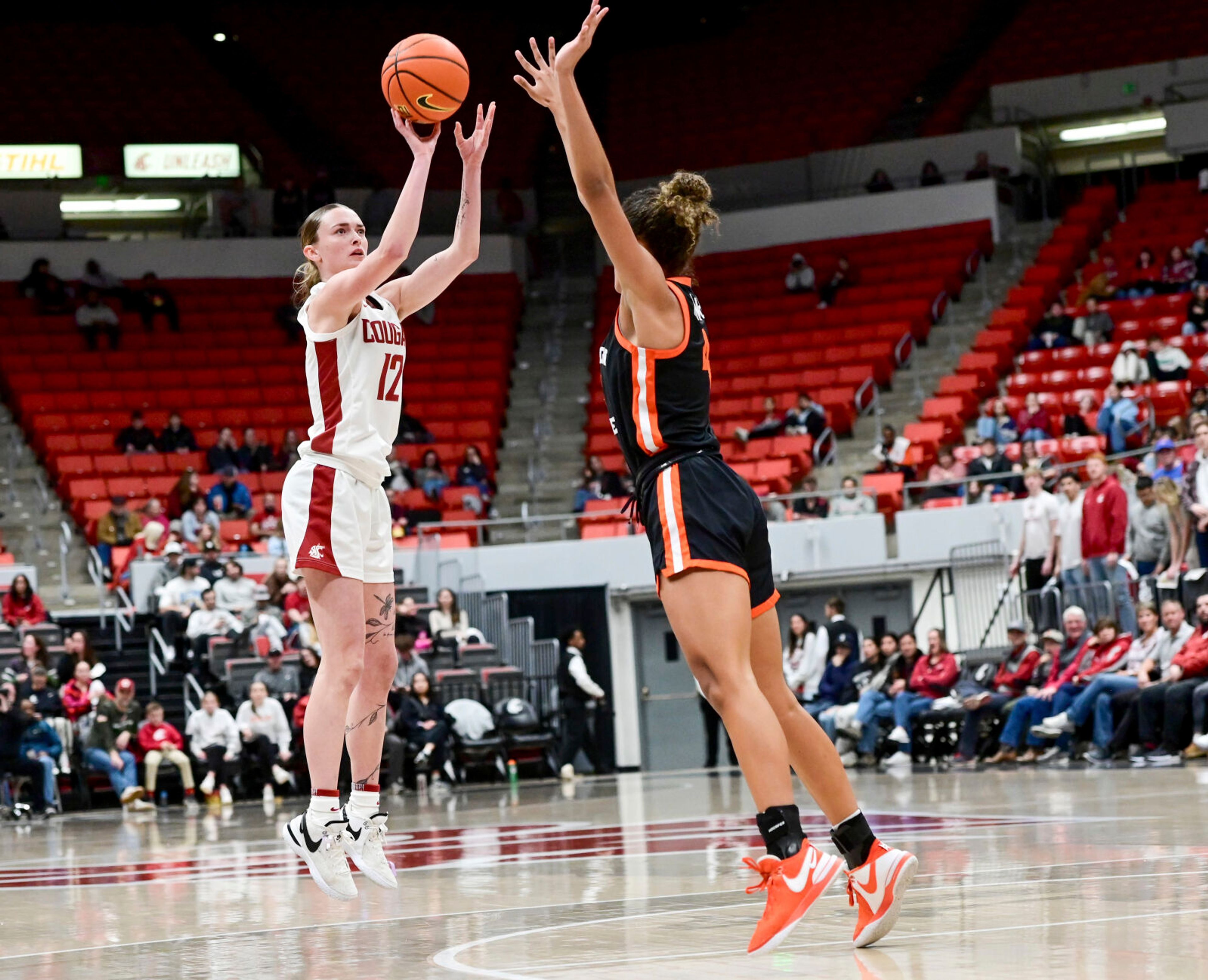 Washington State guard Kyra Gardner, left, jumps for a 3-point shot while being guarded by Oregon State guard Donovyn Hunter, right, during a game Friday at Beasley Coliseum in Pullman.