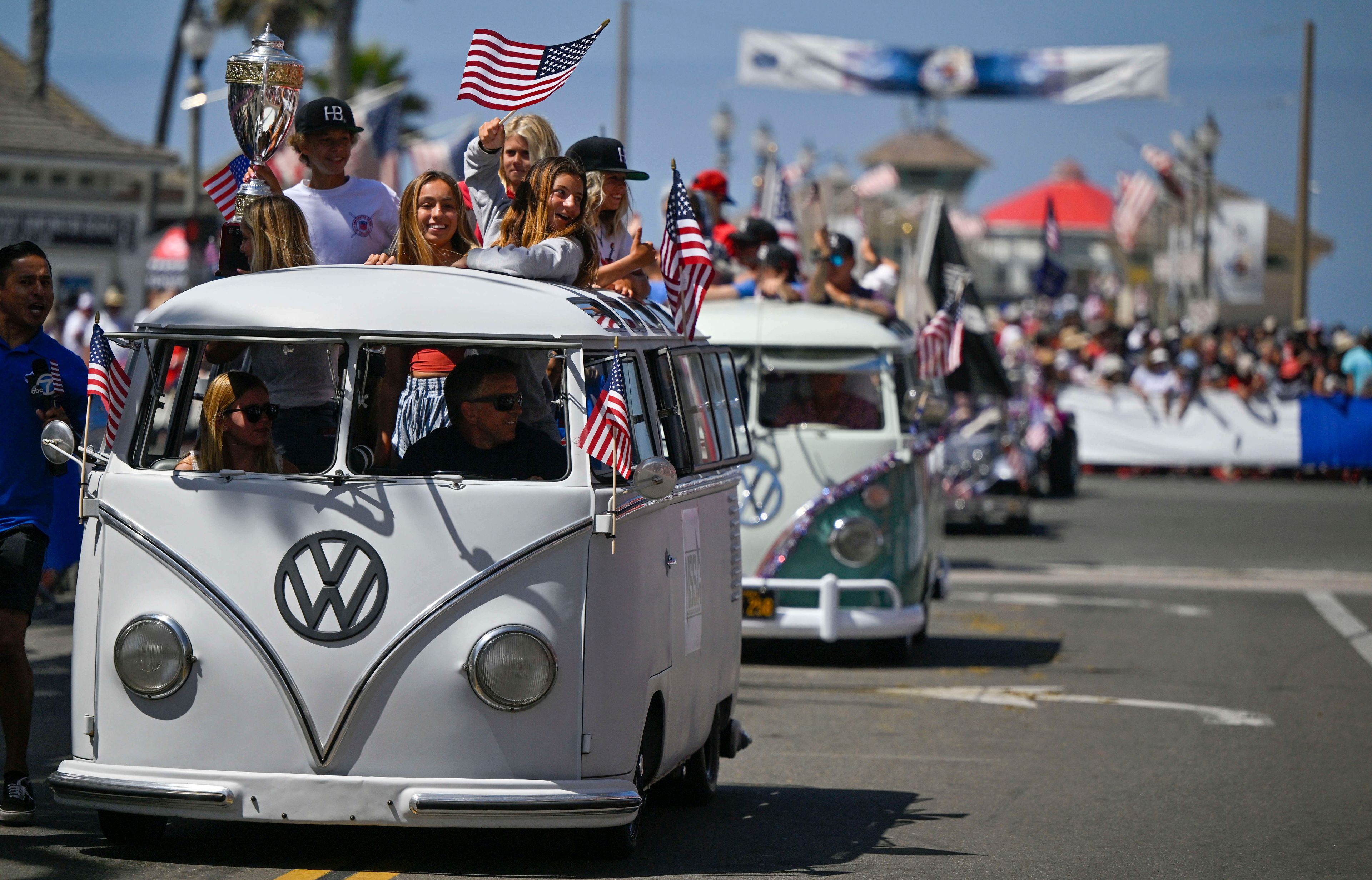 Members of the National Scholastic Surfing Association ride up Main Street during the 118th Huntington Beach 4th of July in Huntington Beach, Calif., on Monday, July 4, 2022. (Jeff Gritchen/The Orange County Register via AP)