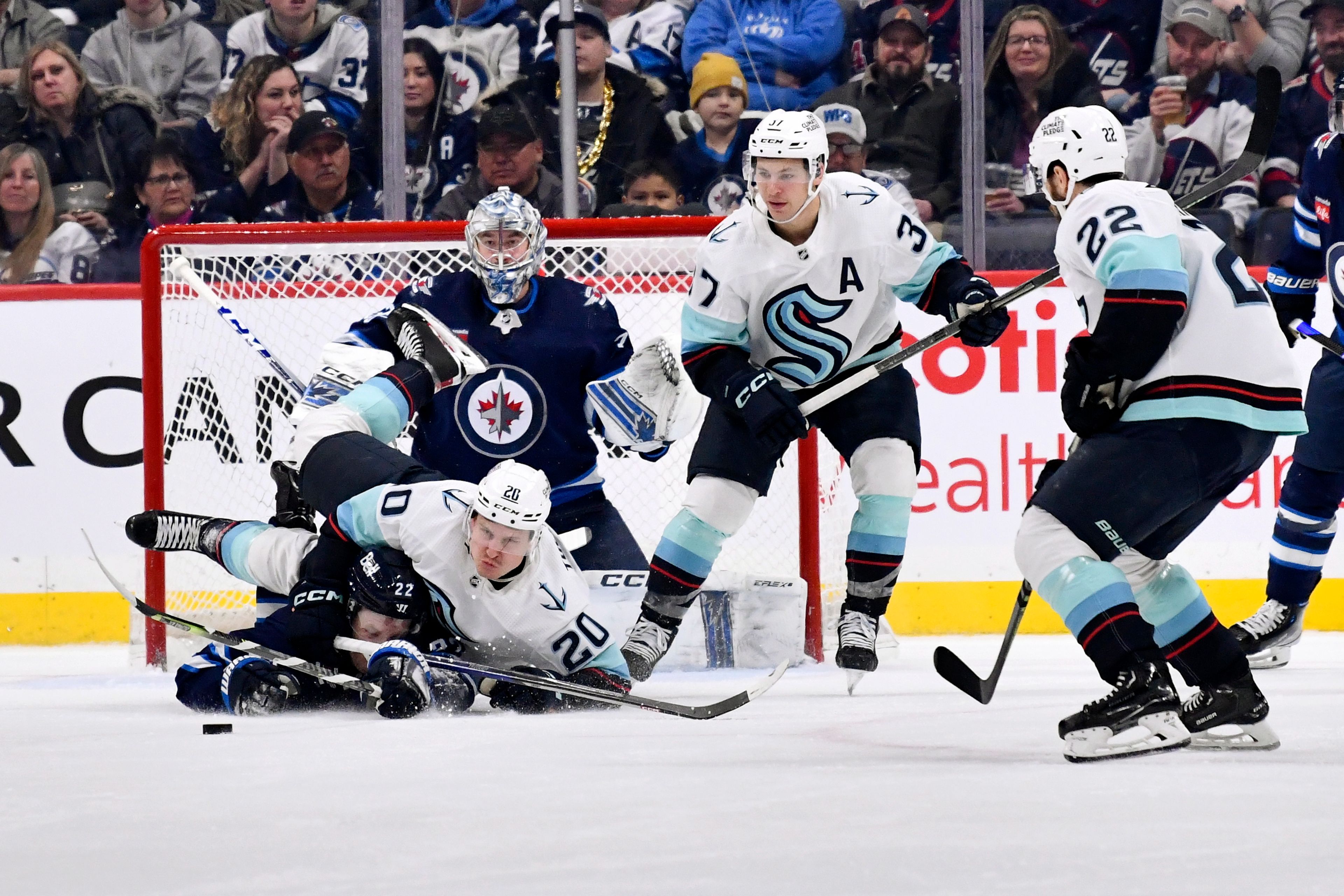 Seattle Kraken's Eeli Tolvanen (20) crashes into Winnipeg Jets' Mason Appleton (22) in front of goaltender David Rittich (33) during the second period of an NHL game in Winnipeg, Manitoba on Tuesday Feb. 14, 2023. (Fred Greenslade/The Canadian Press via AP)