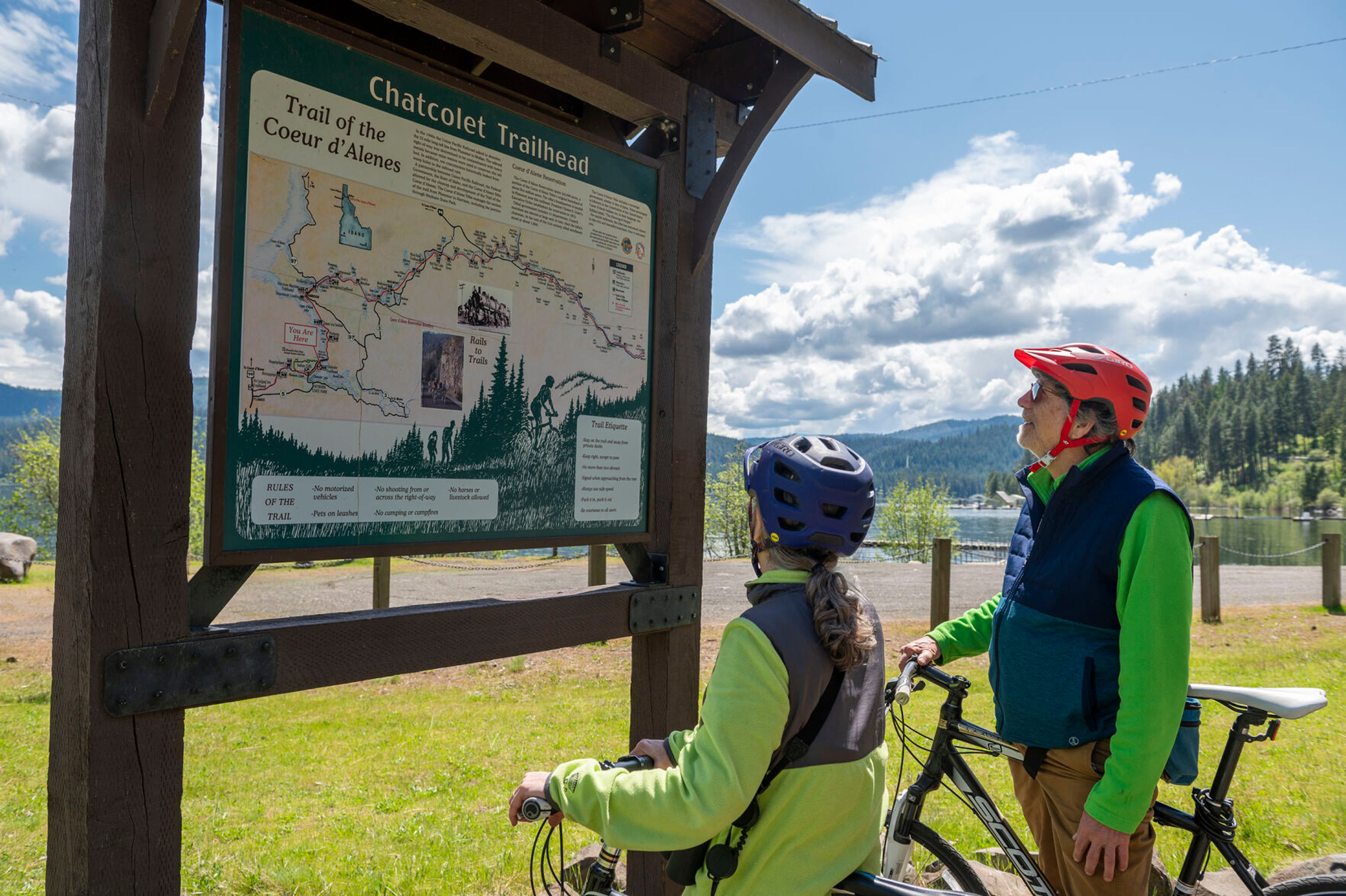 Nancy Holmes, left, and her husband Evan look at a map while taking a break from their afternoon bike ride alongside Trail of the Coeur d’Alene. “It’s a perfect day. We’re naturalists so we’re all about seeing the birds and flowers,” Nancy said.