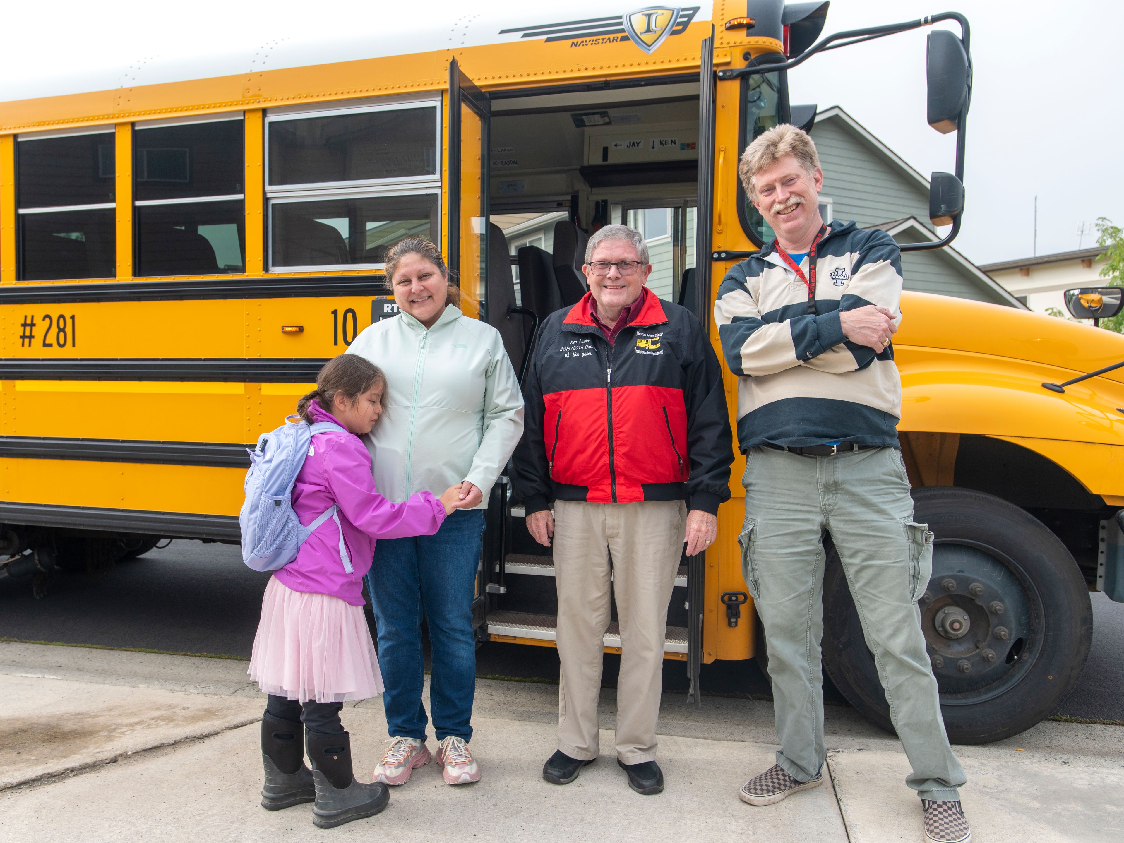 Laren Paul, 8, hugs her mother, Gia, as they pose for a photograph with Moscow School District bus driver Ken Nuhn, middle, and aide Jay Dearien, right, on Thursday. On good days and bad, Nuhn and Dearien greet Laren in Nimipuutimt, the native language of the Nez Perce Tribe, upon pickup and drop-off from school. After the photo, Nuhn and Dearien each departed with a “Ta’ c kul’eewit,” which means “good evening,” in Nimipuutimt.