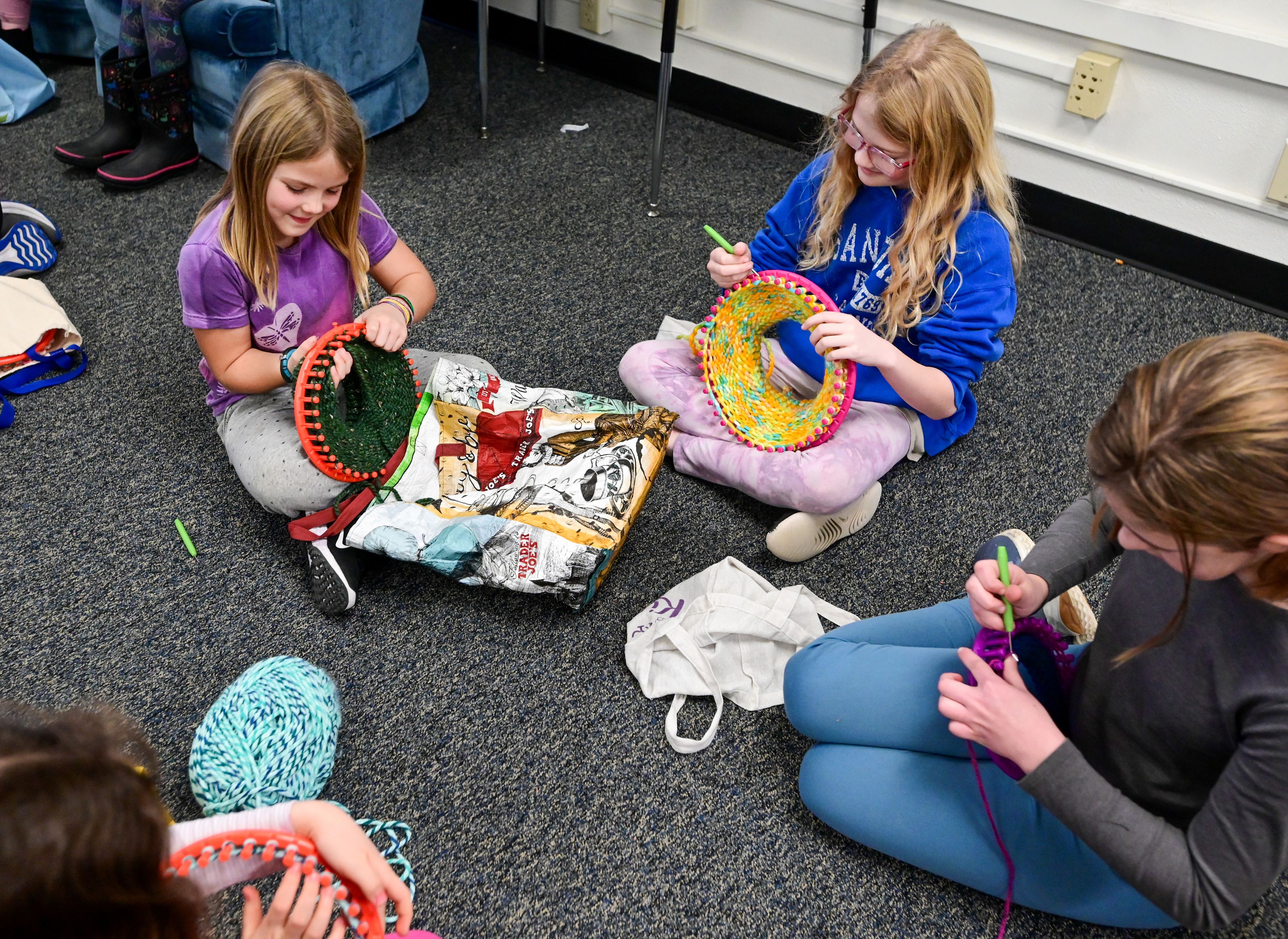 Fourth-graders Eilee Lowry, top left, Georgia Lisher, and fifth-grader Isa Thomas, right, sit in a circle to knit hats using round looms at Lena Whitmore Elementary School in Moscow on Monday.