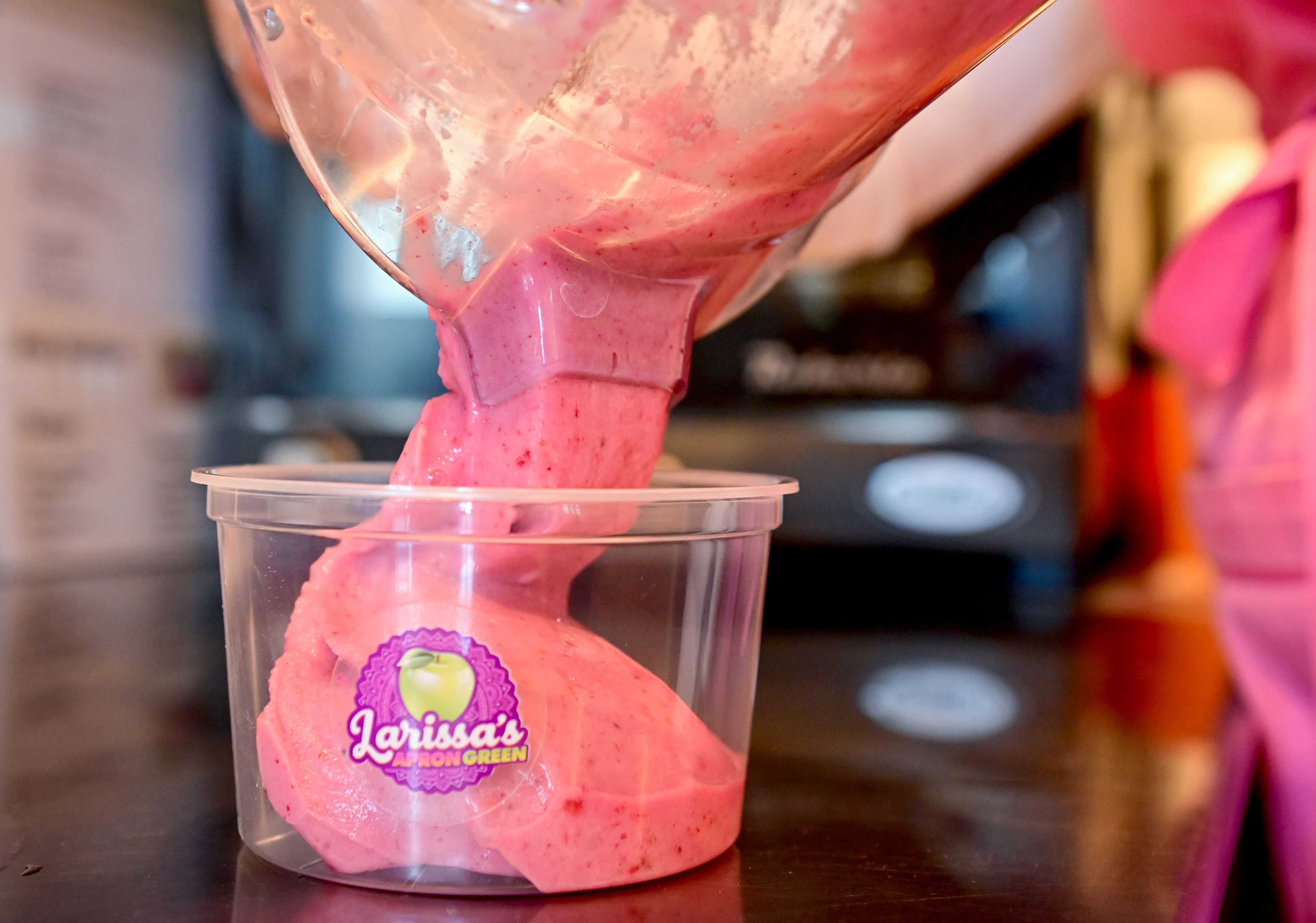 Seeber pours the base of a Pink Paradise bowl into a serving container at Larissas Apron Green  in Pullman. The bowl is made out of dragon fruit, coconut milk, banana, strawberry and agave.