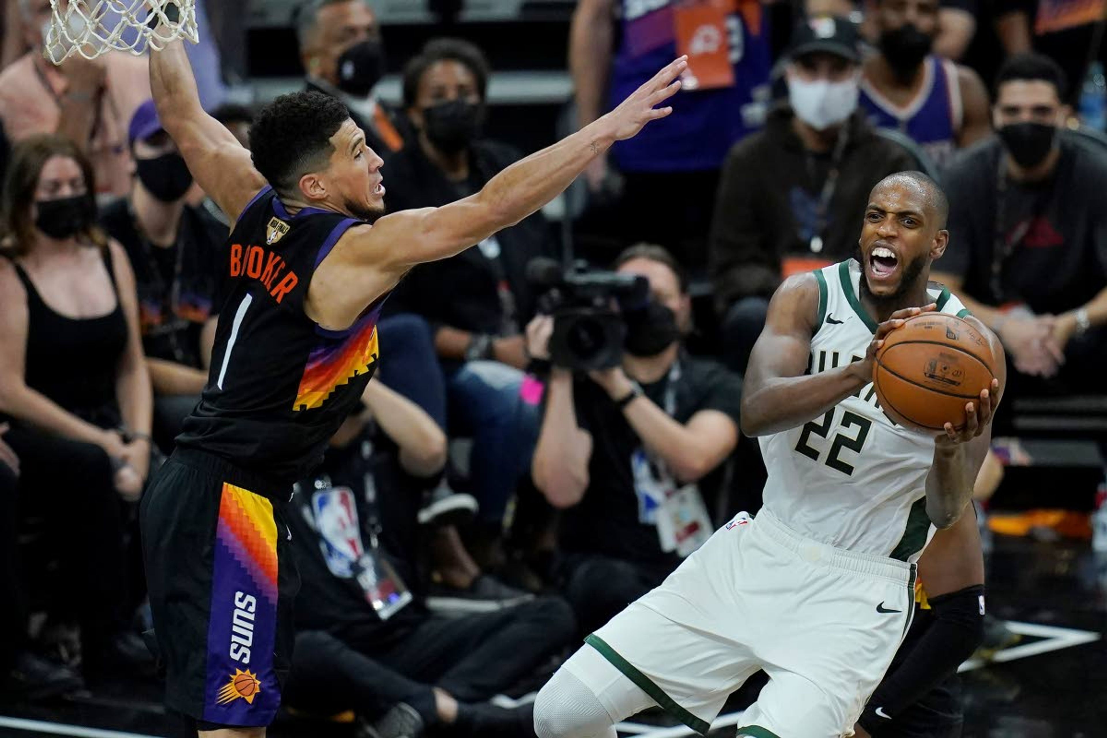 Milwaukee Bucks forward Khris Middleton (22) is defended by Phoenix Suns guard Devin Booker during the second half of Game 2 of basketball's NBA Finals, Thursday, July 8, 2021, in Phoenix. (AP Photo/Ross D. Franklin)