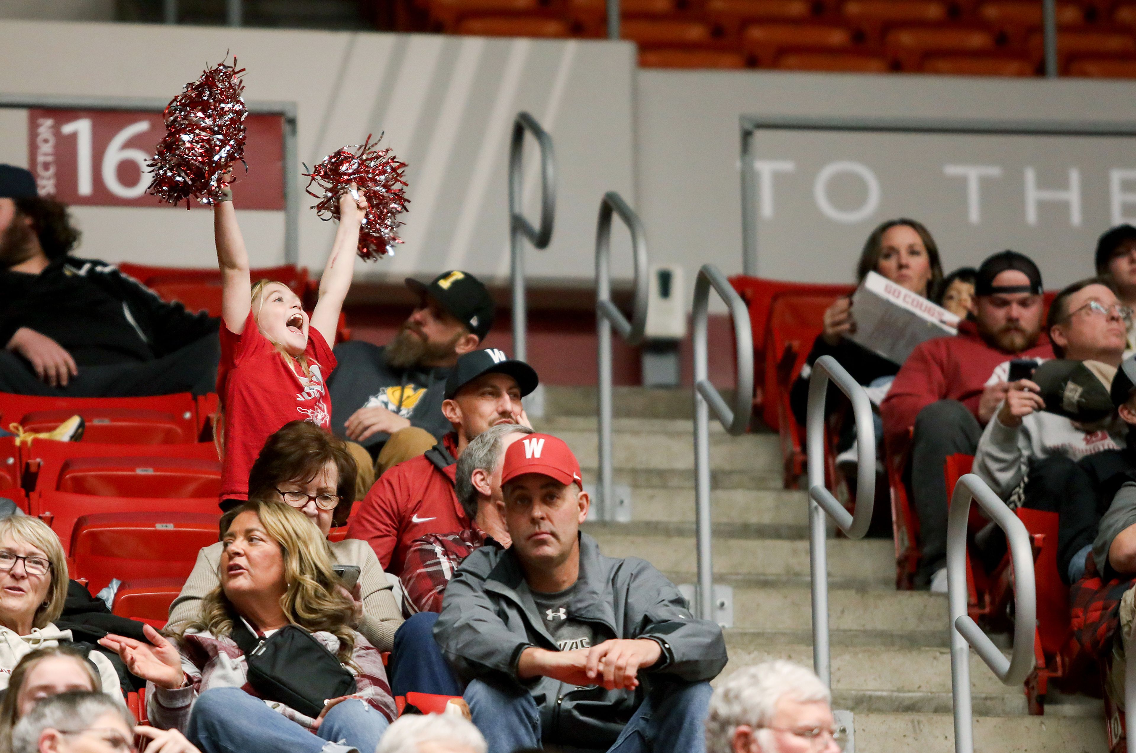 A young fan raises pompoms in the air to cheer from the stands during the Battle of the Palouse game between Washington State and Idaho Monday at Beasley Coliseum in Pullman.