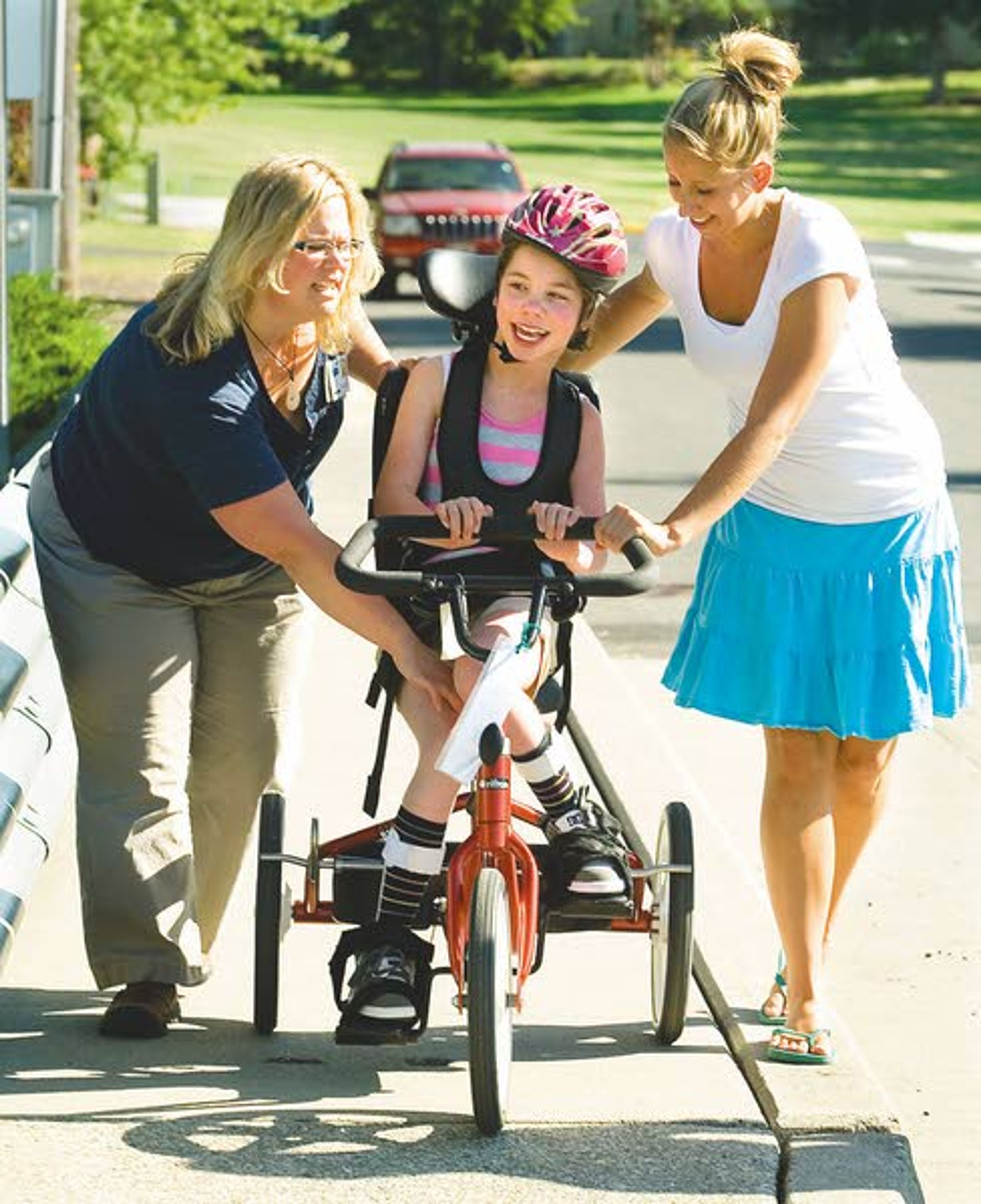 Maya Salada, 12, smiles while riding her trike with Lori Mages, left, and Shandray Lukehart in the Gritman Therapy Solution bike group in Moscow on Tuesday. Mages is a physical therapist with Griman Therapy Solutions. Lukehart is Salada's care giver.