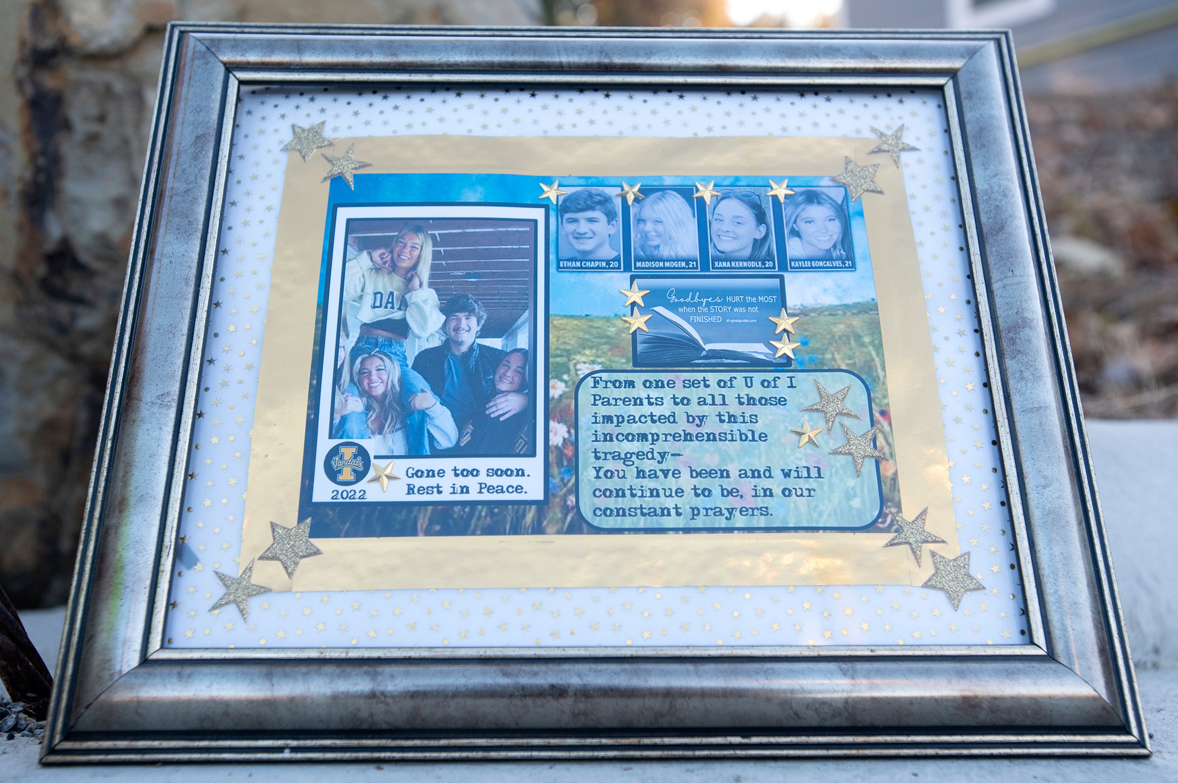 A framed picture of the four University of Idaho students slain in a quadruple homicide rests next to a teddy bear and bouquets of flowers Monday outside the crime scene on King Road in Moscow.