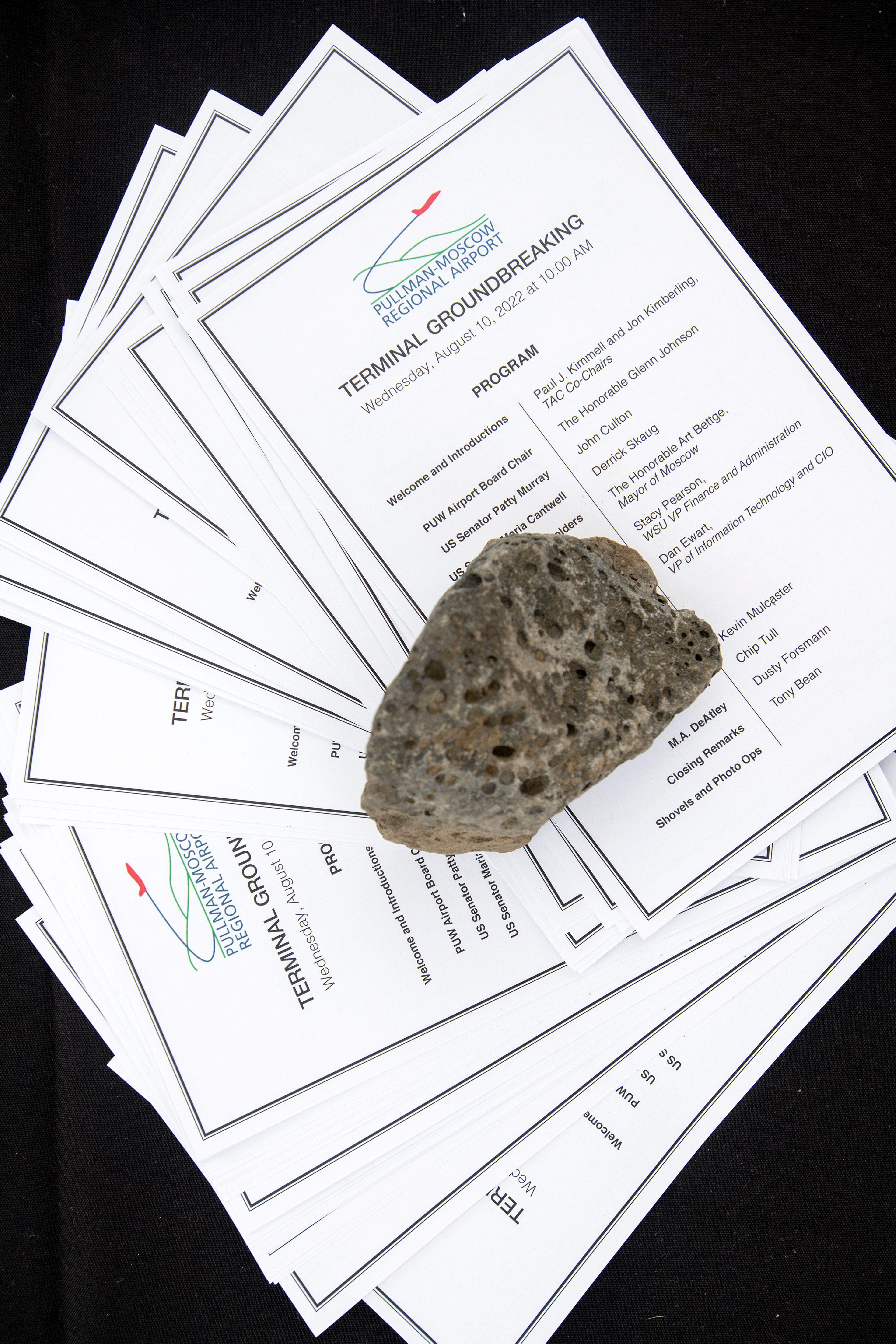 A rock is used as a paperweight to hold programs on a table during a groundbreaking event for the new Pullman-Moscow Regional Airport terminal.