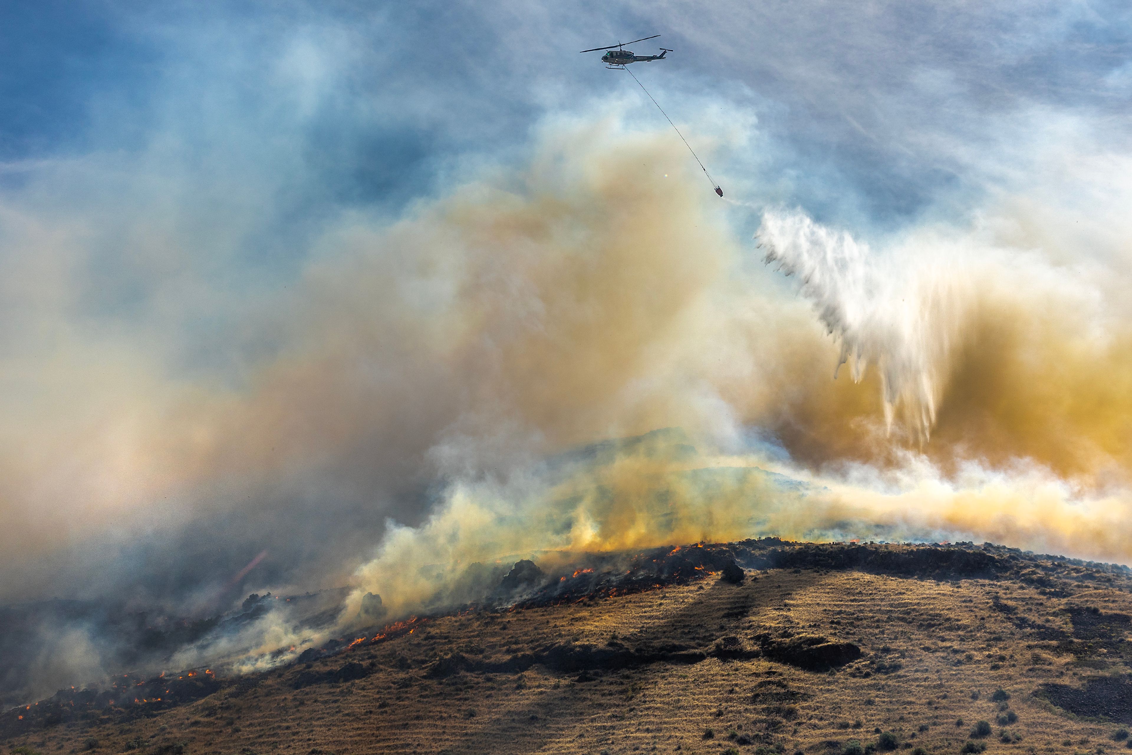 A helicopter makes a drop on a fire moving along the hillside by Nisqually John Landing off of Wawawai Road on Friday.