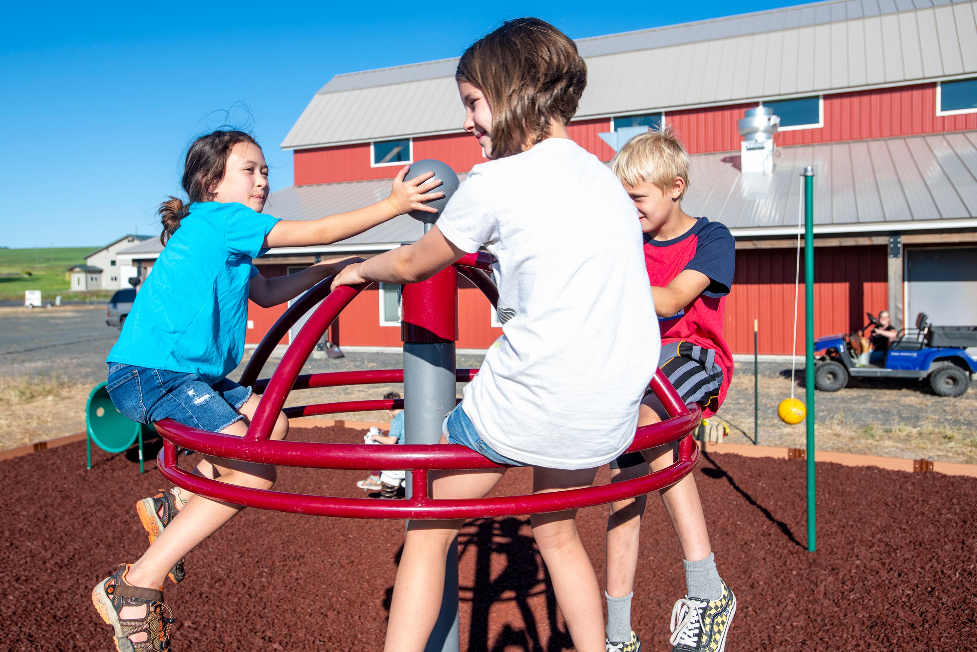 Olivia Bartlett, 9, from left, Lucy Merten-Daily, 9, and Wyatt Humphrey, 8, play on a piece of equipment Thursday evening at the Viola Community Center playground.