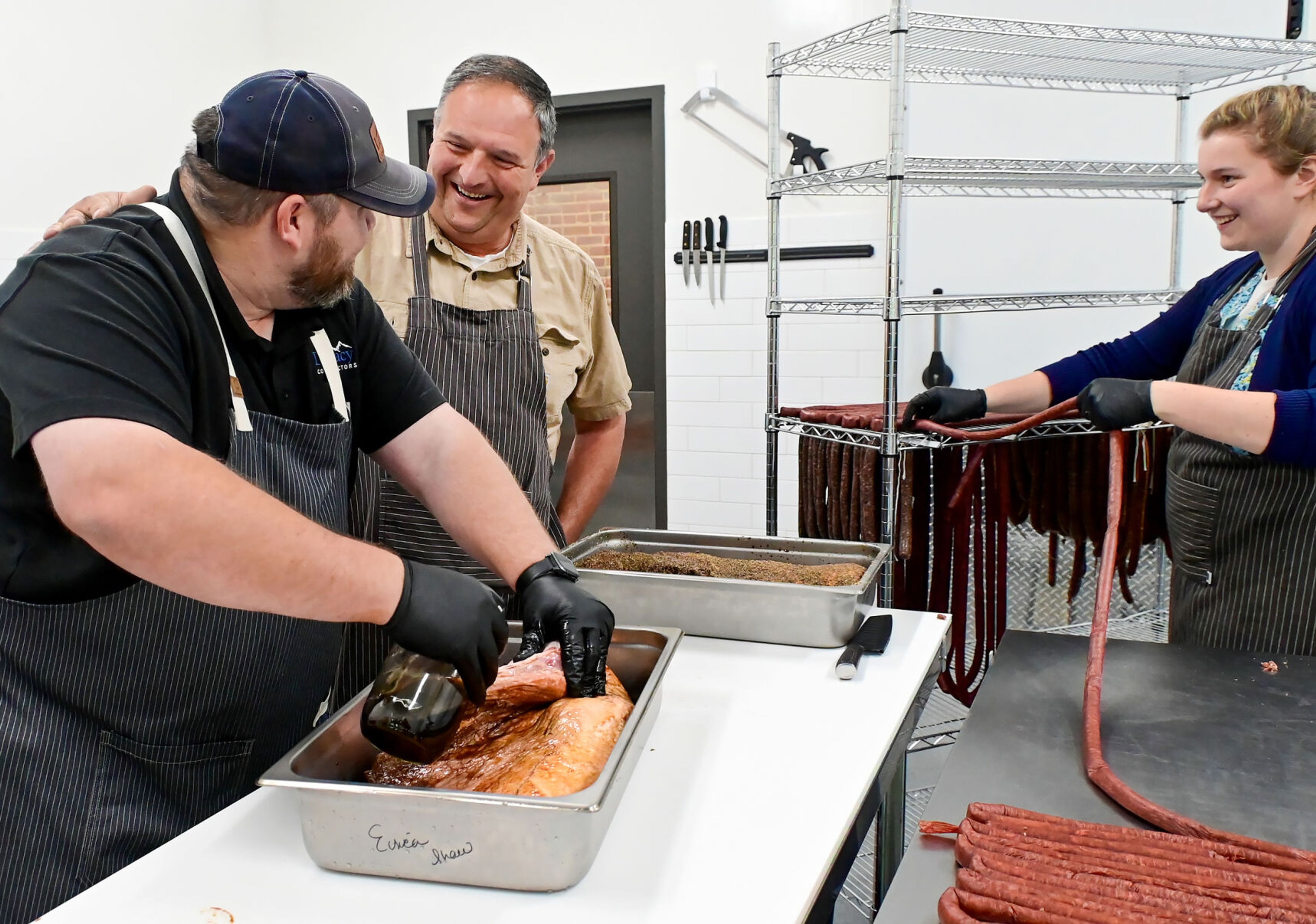 Dale Shaw, from left, Gary Moore and Hanna Moore work to prepare brisket, left, and meat sticks at The Butcher Shop on Friday in Deary.