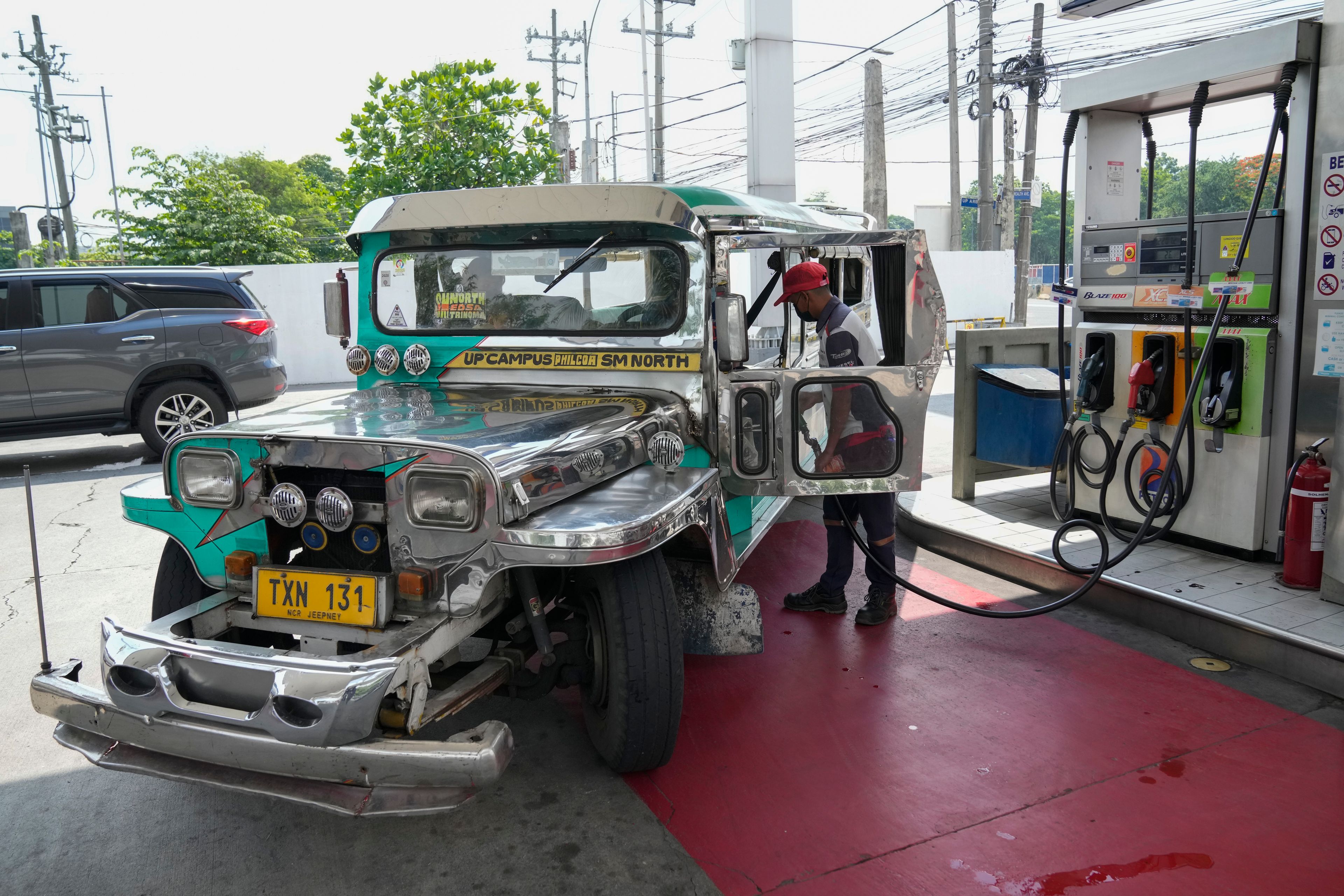 A passenger jeepney driver refuels his vehicle at a gasoline station in Quezon City, Philippines on Monday, June 20, 2022. Around the world, drivers are looking at numbers on the gas pump and rethinking their habits and finances. (AP Photo/Aaron Favila)