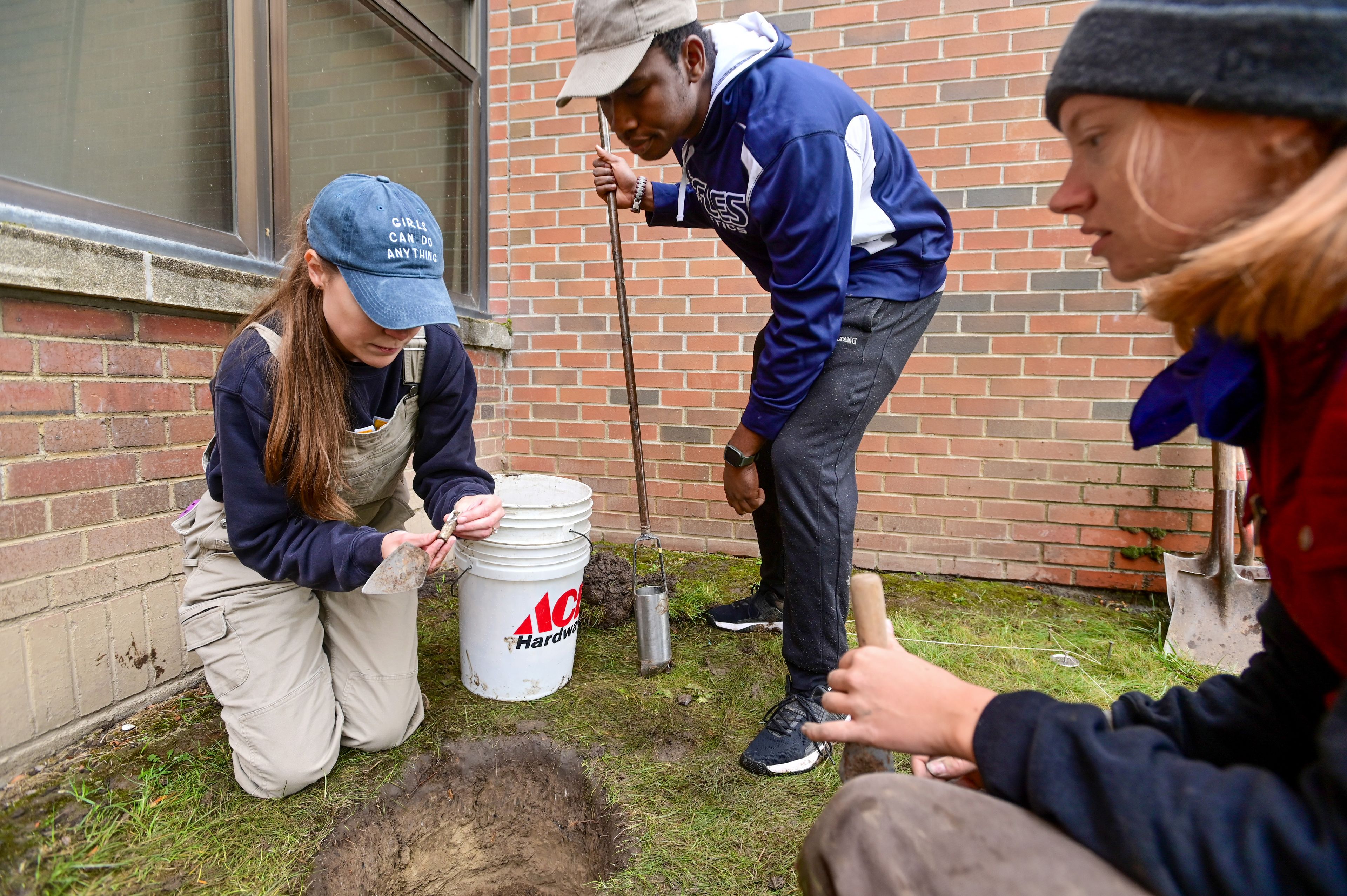 Katrina Eichner, an assistant professor at the University of Idaho and a co-director of the excavation project at Moscow High School, shows undergraduate students Daniel Bangudu, center, and Mattie Lustig an artifact found at one of the dig sites at the school on Tuesday.