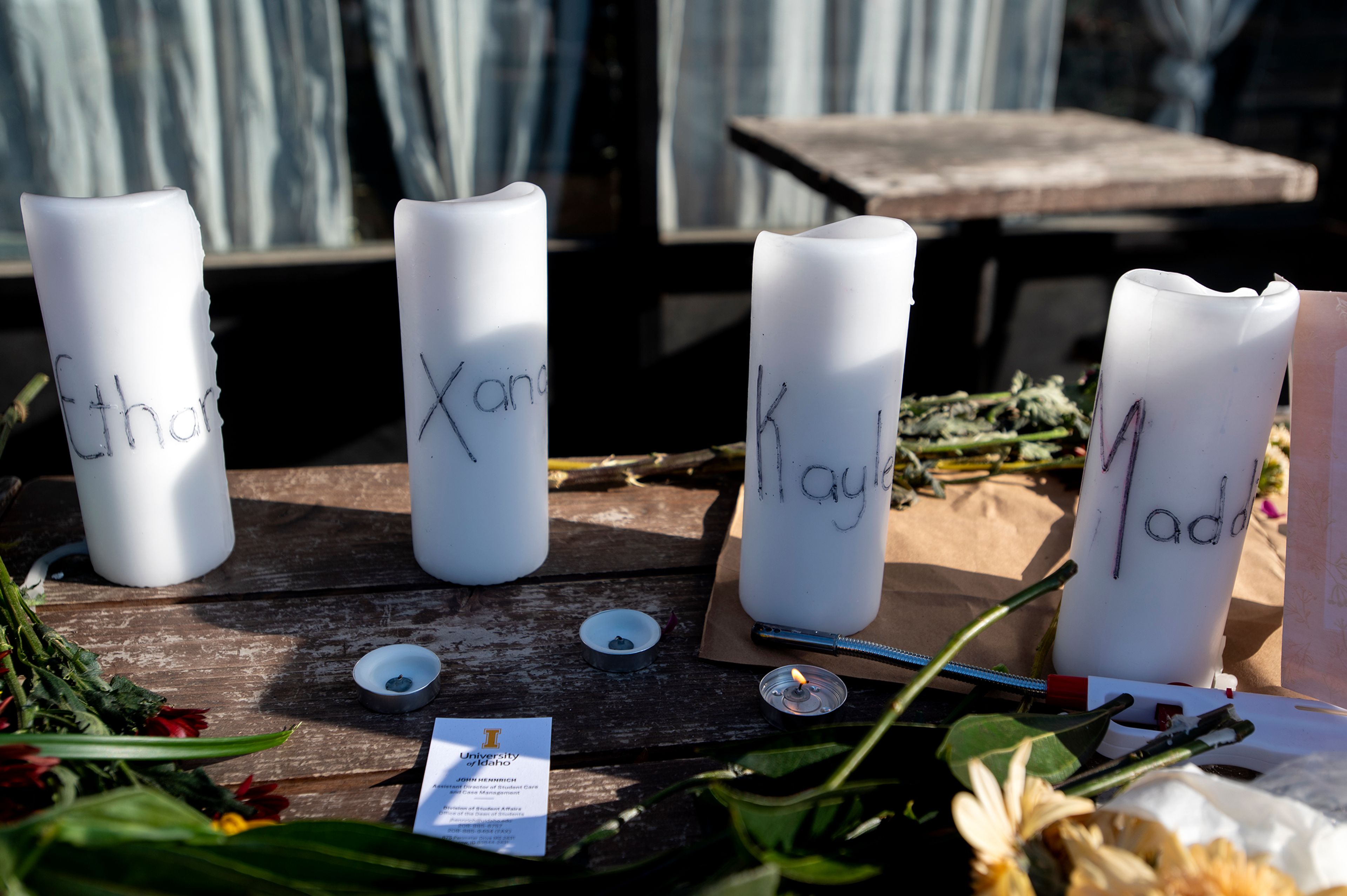 A single flame flickers amongst flowers in honor of four deceased University of Idaho students, including Madison Mogen and Xana Kernodle, who worked at Mad Greek in downtown Moscow, at a memorial put together by coworkers outside of the restaurant on Tuesday.