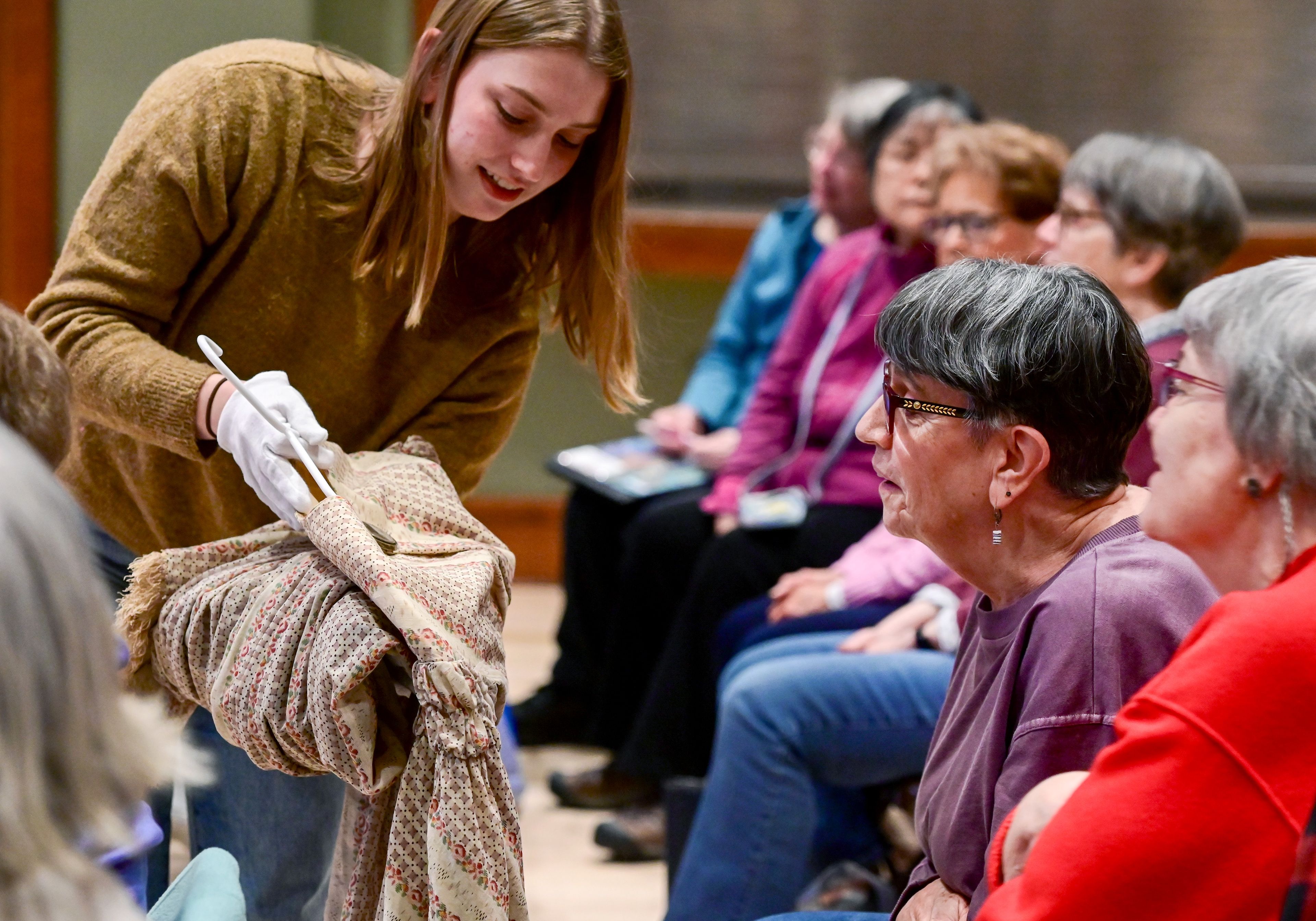 Cameron Nielson, left, a first-year masters student in costume construction at the University of Idaho, carries pieces from the Leila Old Historic Costume Collection for the audience to view, including Joy Stotz, center, and Darlene Billing, right, at the 1912 Center in Moscow on Tuesday.