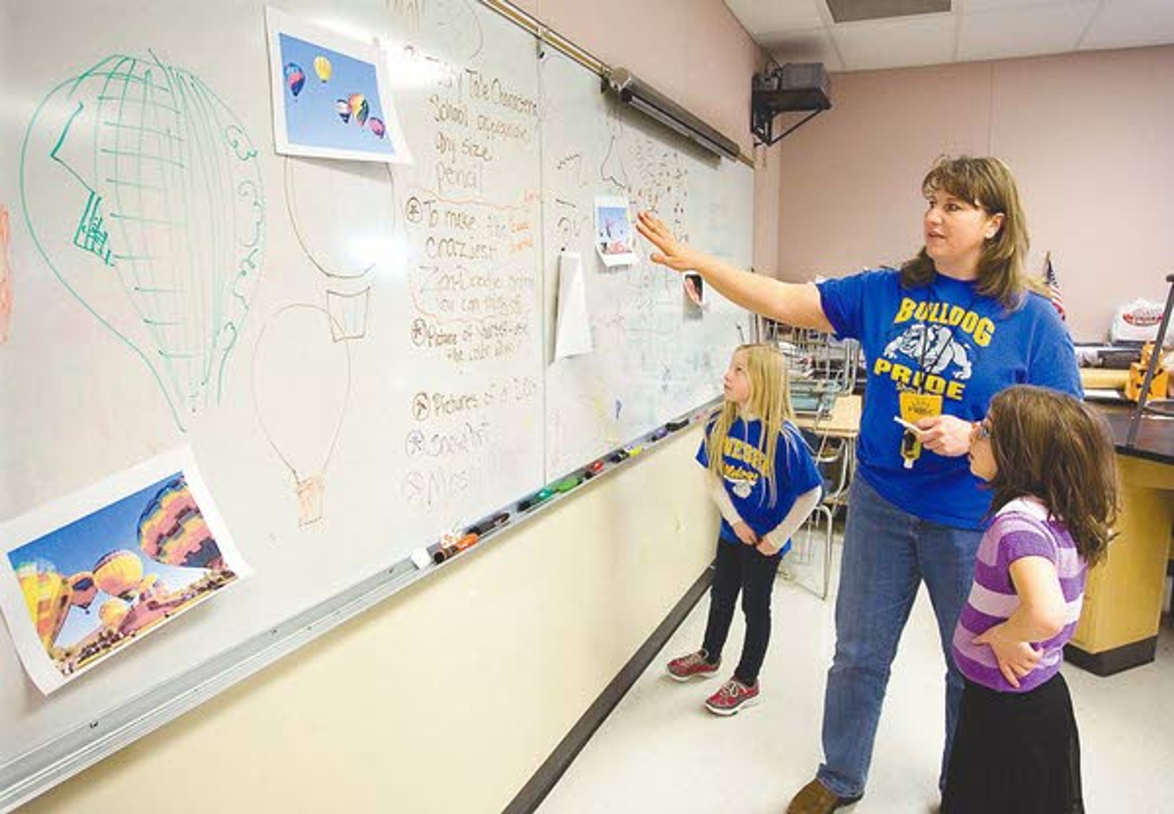 Rosanna Cartwright, center, talks to third-graders Ella Kappus, left, and Delia Hubbard about an art project at Genesee School on Thursday. Cartwright teaches the SPARK! Art Club at the school.