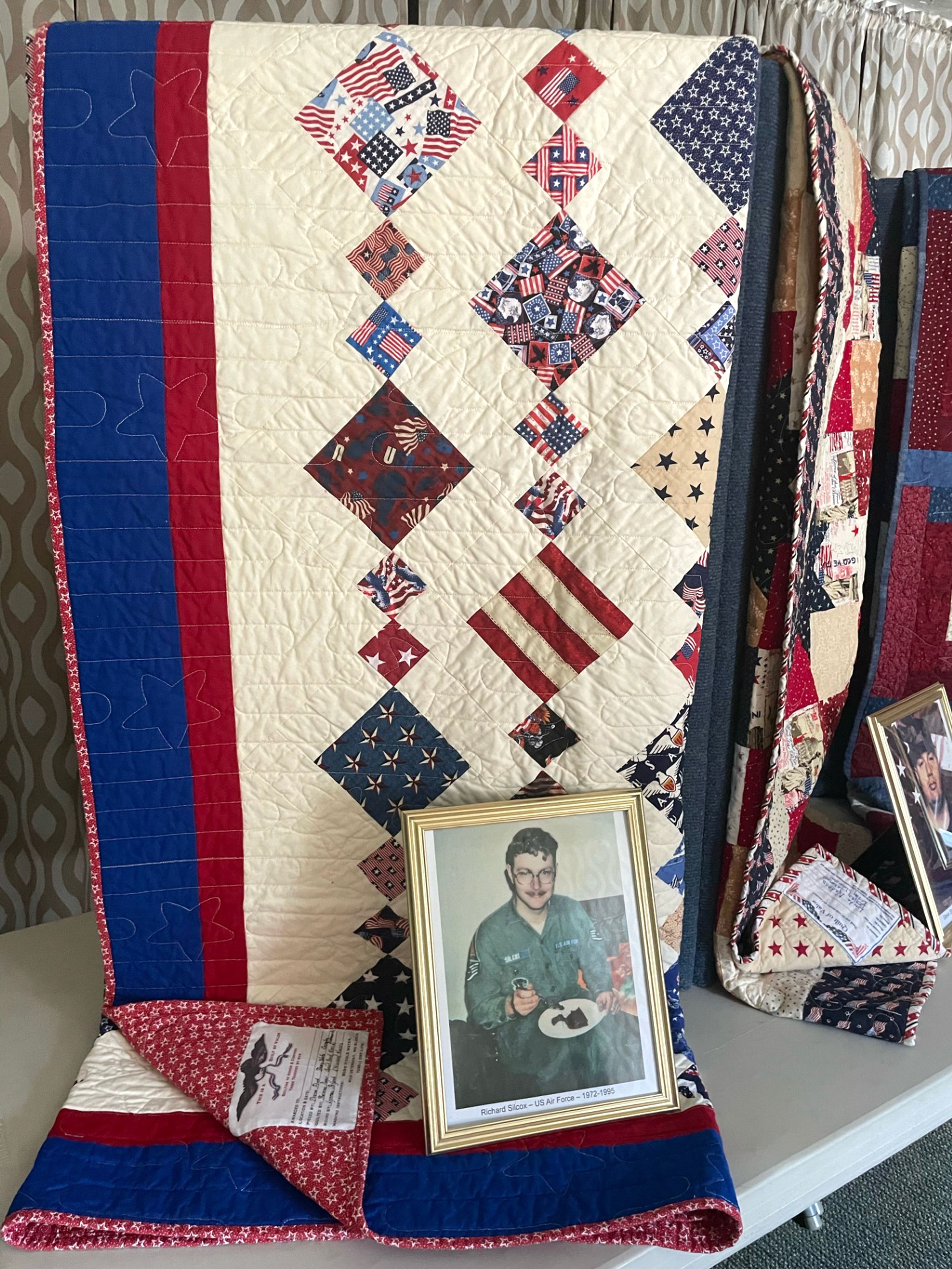 A picture of Richard Silcox, Air Force, sits with his quilt of valor.