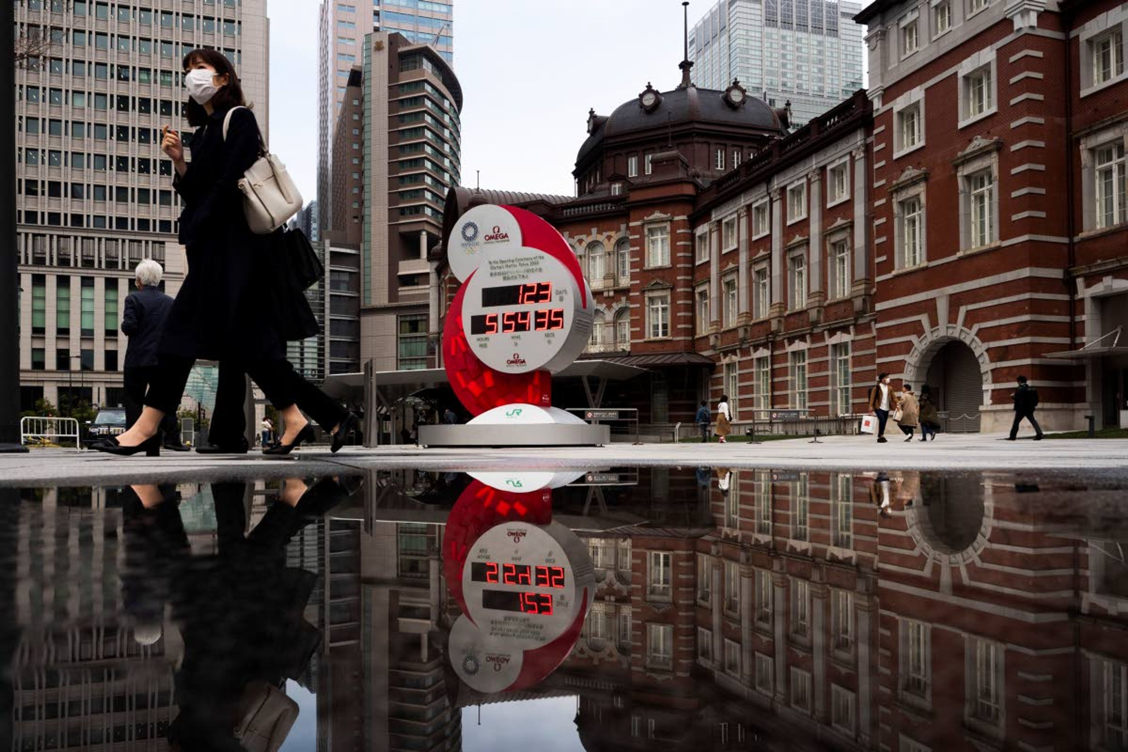 FILE - In this March 23, 2020, file photo, countdown clock for the Tokyo 2020 Olympics is reflected in a puddle of water outside Tokyo Station in Tokyo. IOC officials say the Tokyo Olympics will open on July 23 and almost nothing now can stop the games from going forward. (AP Photo/Jae C. Hong, File)