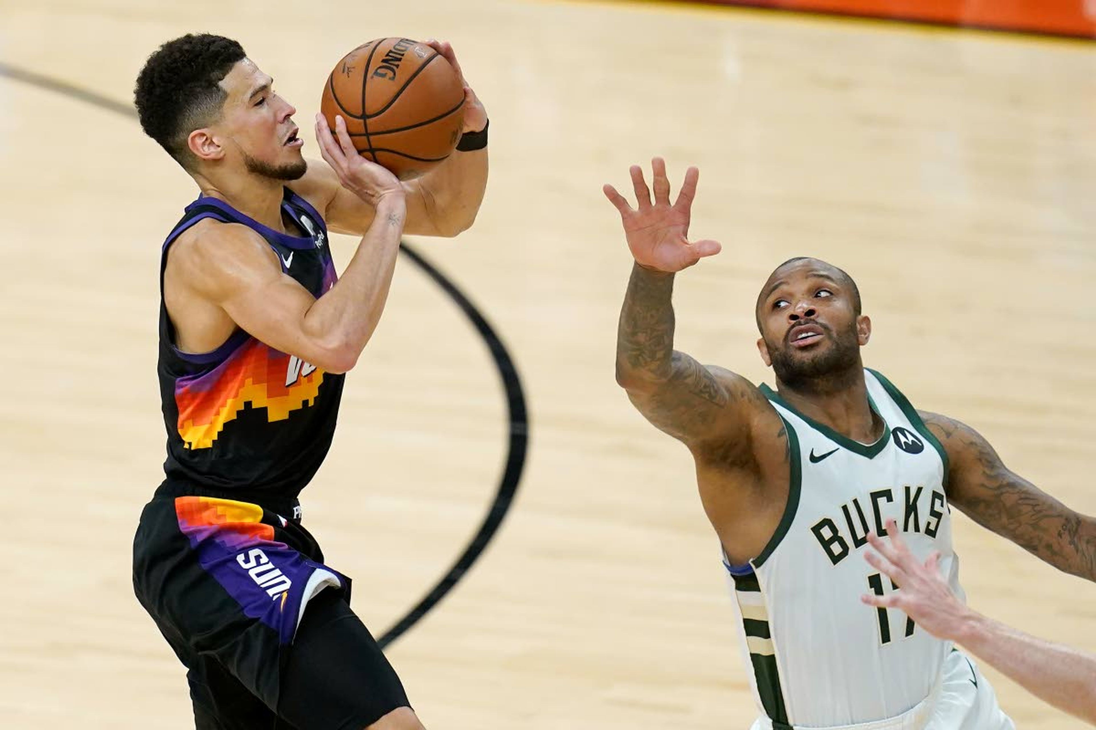 Phoenix Suns guard Devin Booker, left, shoots against Milwaukee Bucks forward P.J. Tucker during the second half of Game 2 of basketball's NBA Finals, Thursday, July 8, 2021, in Phoenix. (AP Photo/Ross D. Franklin)