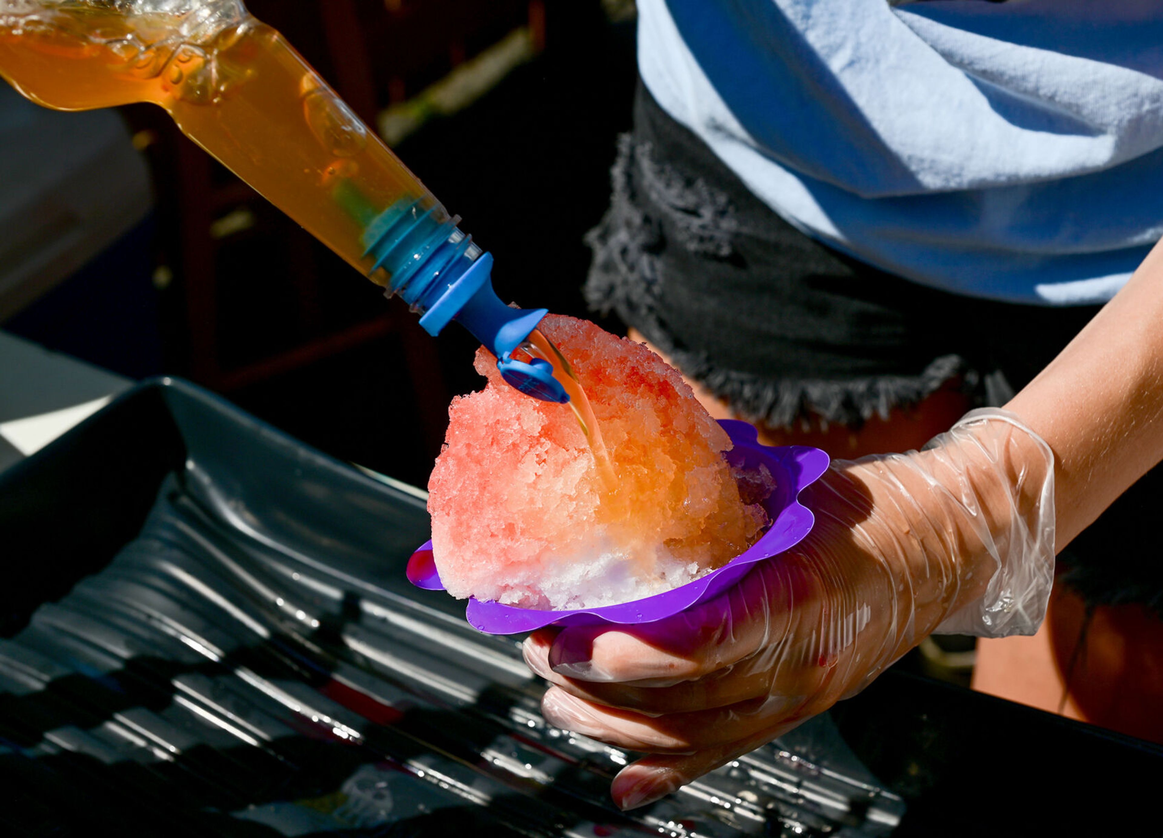 A snow cone is topped with orange syrup by employee Alyssa Goetze at the Shiver Shack in Pullman on Tuesday.