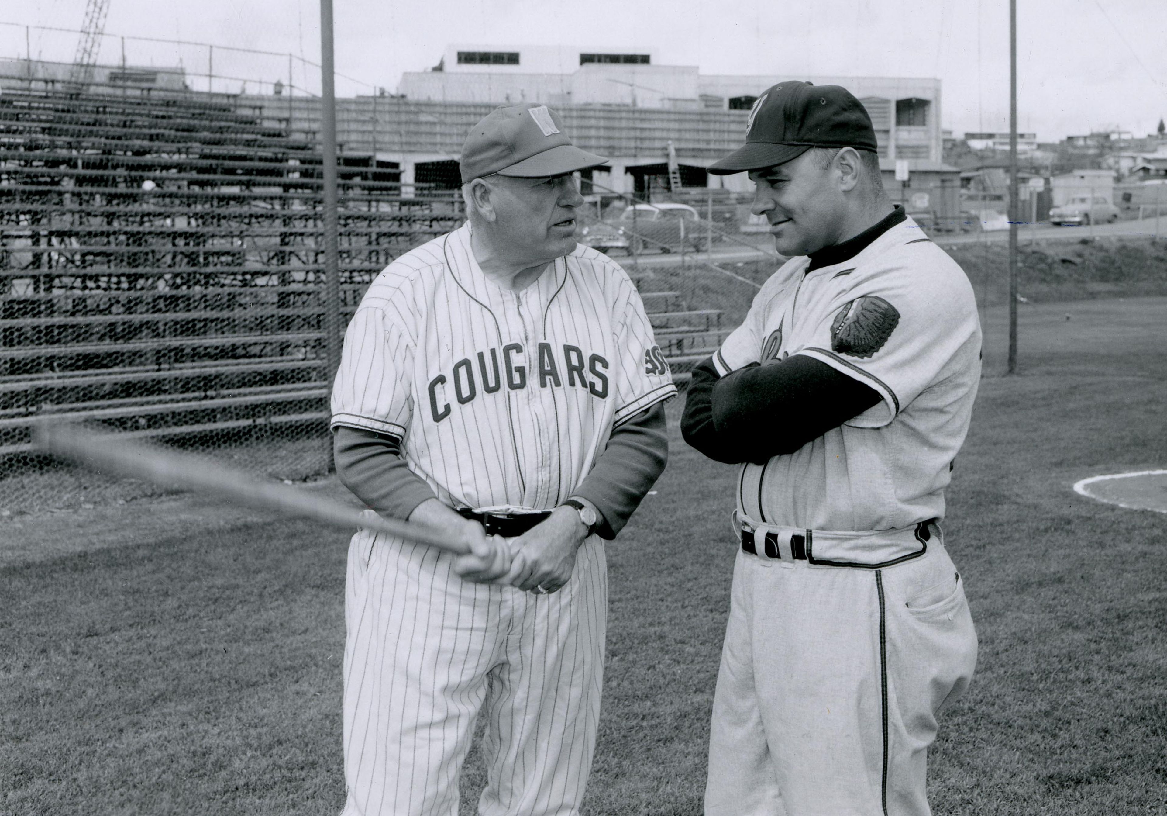 Washington State University head coach Buck Bailey, left, compares notes with his former player, then Yakima Bears coach, and his eventual successor, Bobo Brayton on April 21, 1961. Streit-Perham is under construction in the background.