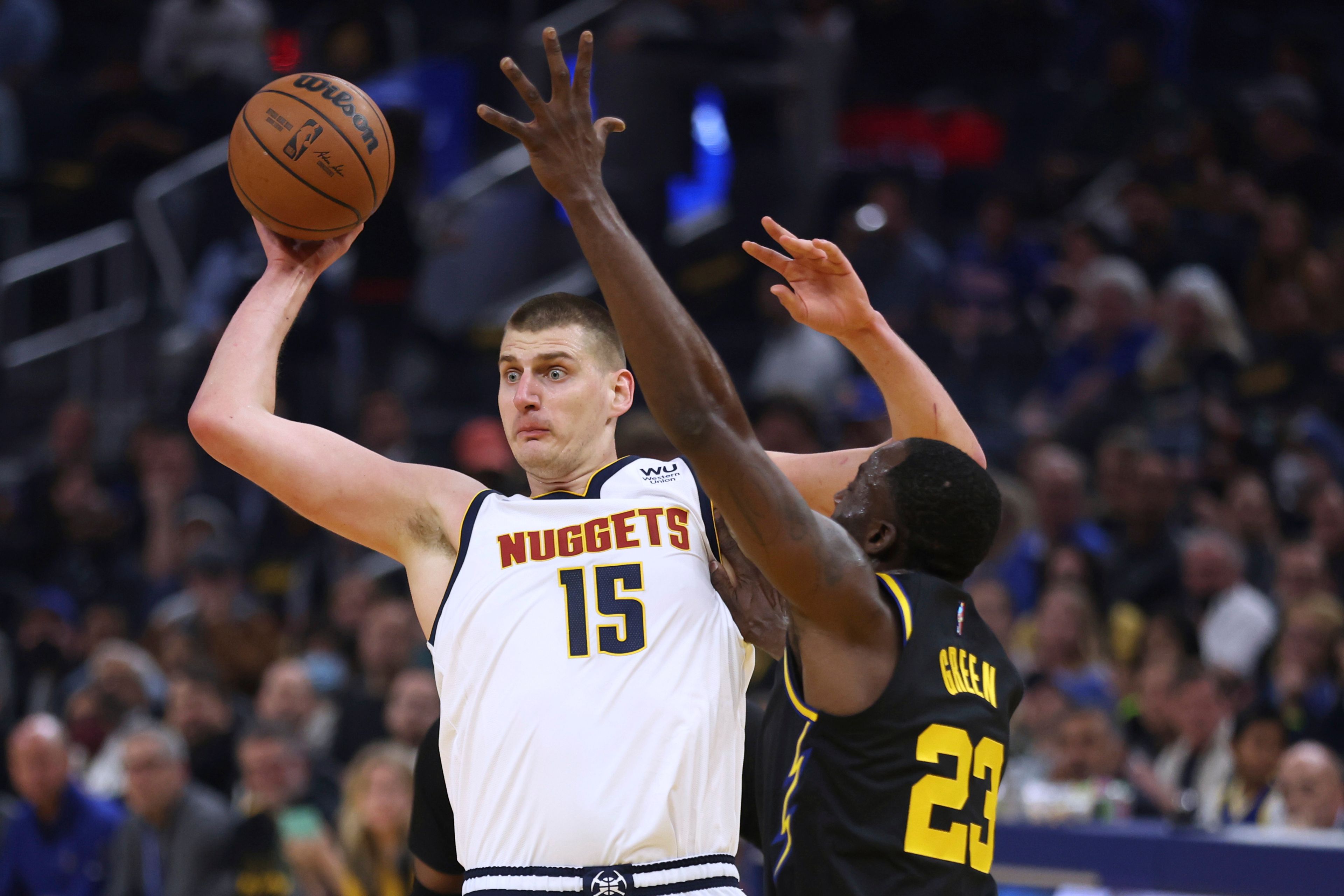 Denver Nuggets center Nikola Jokic (15) passes the ball as Golden State Warriors forward Draymond Green (23) defends during the first half of Game 5 of an NBA basketball first-round playoff series in San Francisco, Wednesday, April 27, 2022. (AP Photo/Jed Jacobsohn)