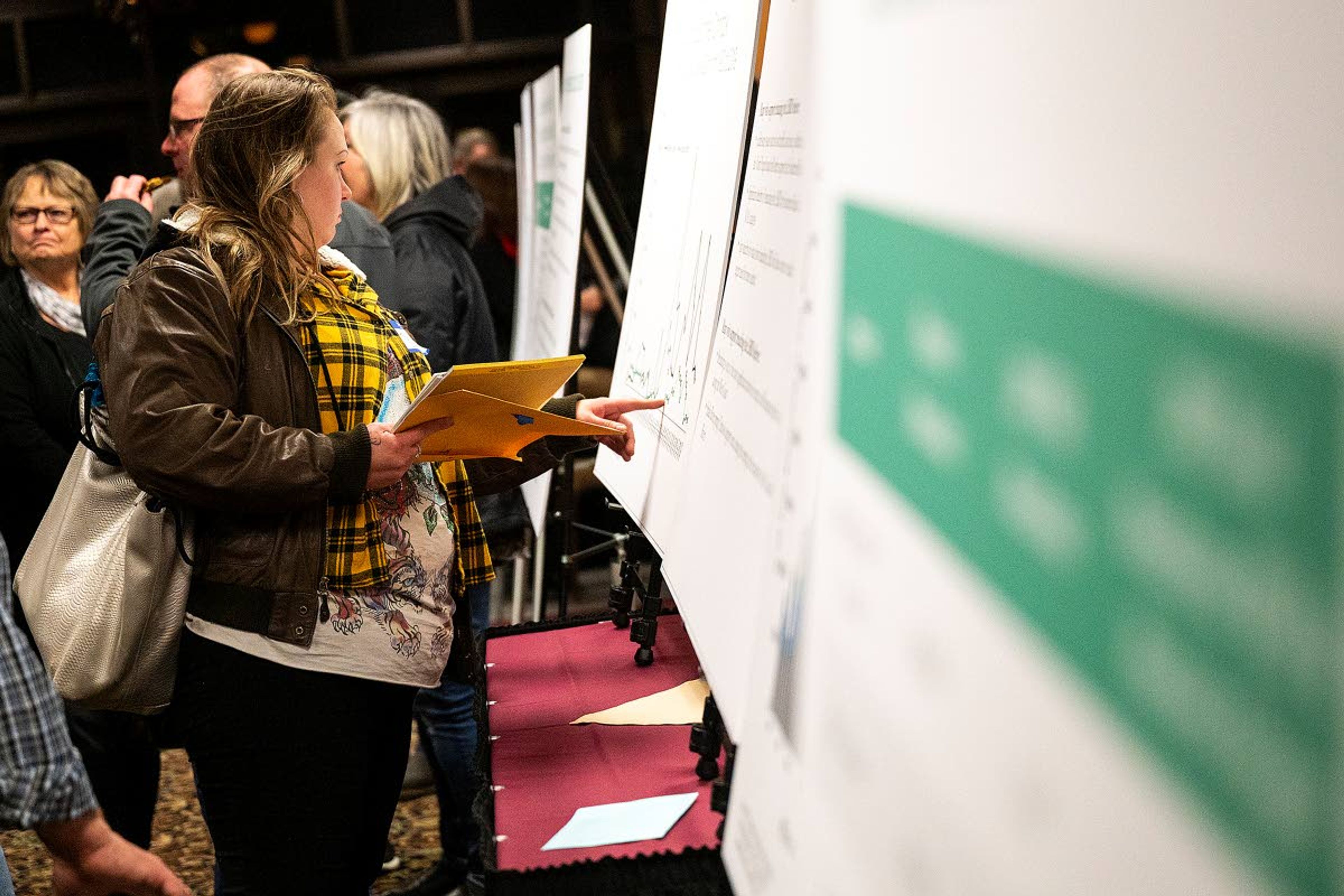 People analyze large posters explaining some of the points that were brought up in the study commissioned by Washington Gov. Jay Inslee about the public opinion on the potential removal of the four lower Snake River dams prior to the start of a meeting on the report on Tuesday night in Clarkston.