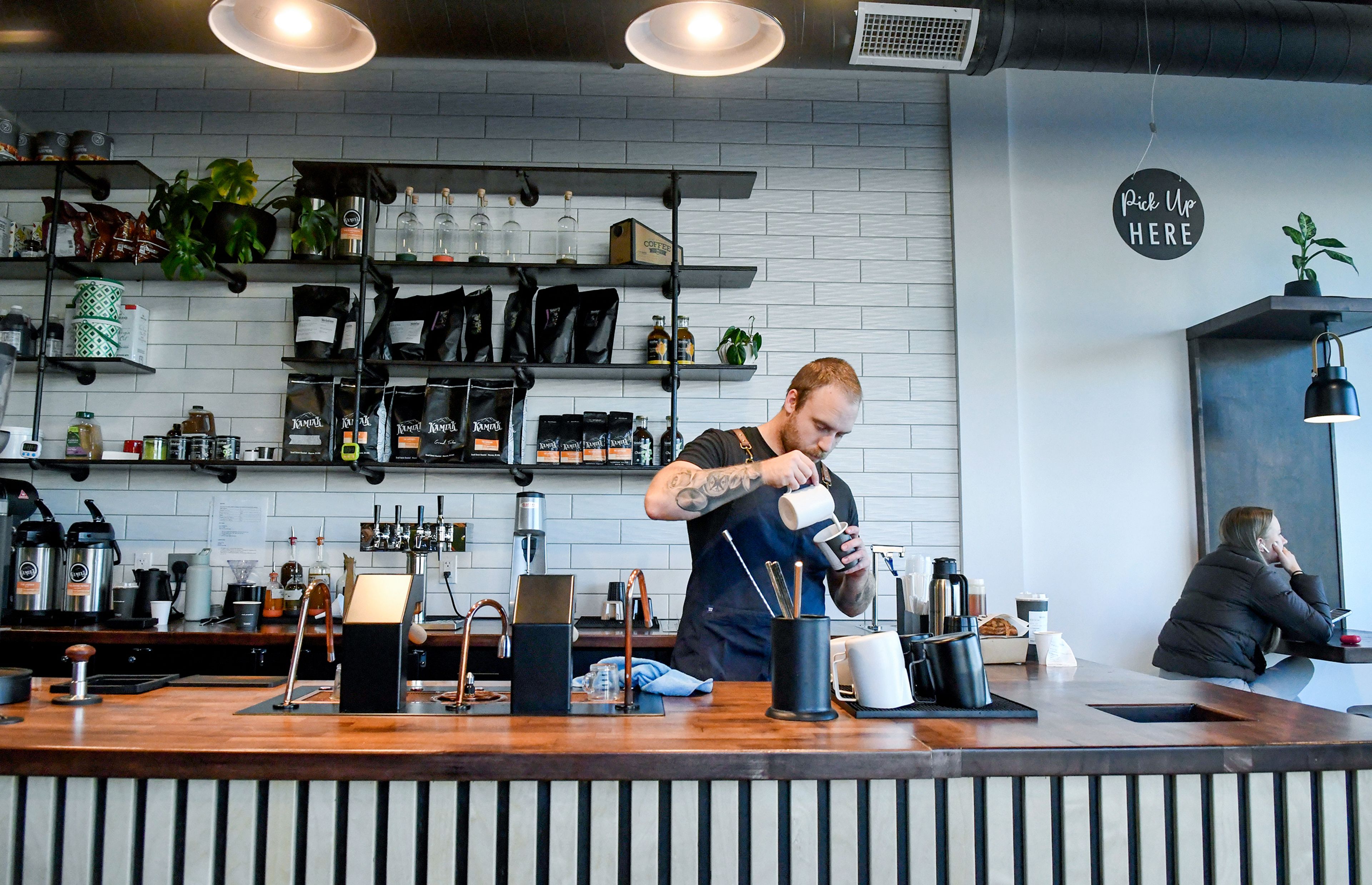 Tyler Kennedy, an owner of Knead Cafe & Patisserie, prepares drinks at the business. 