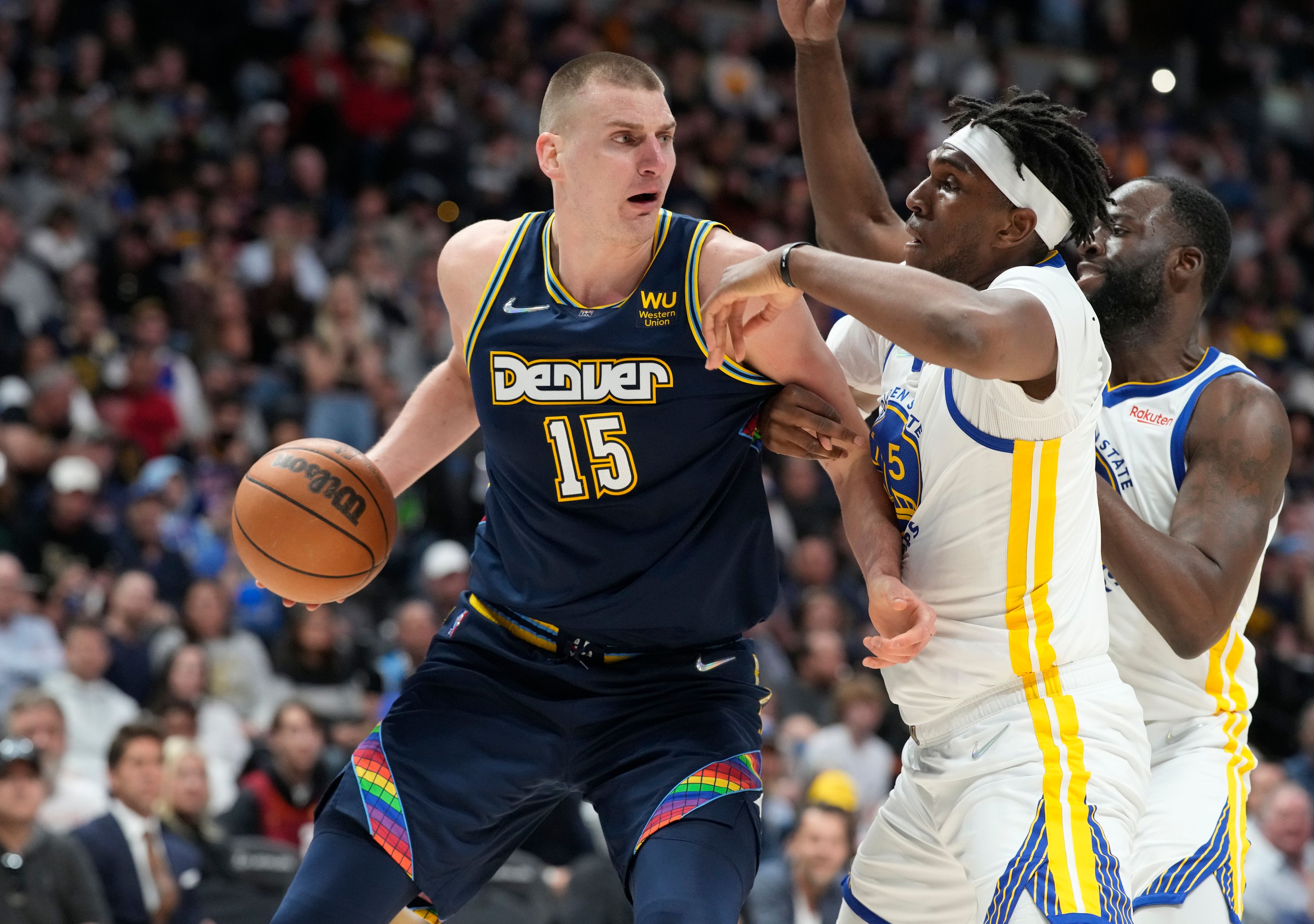 Nuggets center Nikola Jokic, left, looks to pass the ball as Warriors center Kevon Looney, center, and forward Draymond Green defend in a playoff game April 24 in Denver. Associated Press