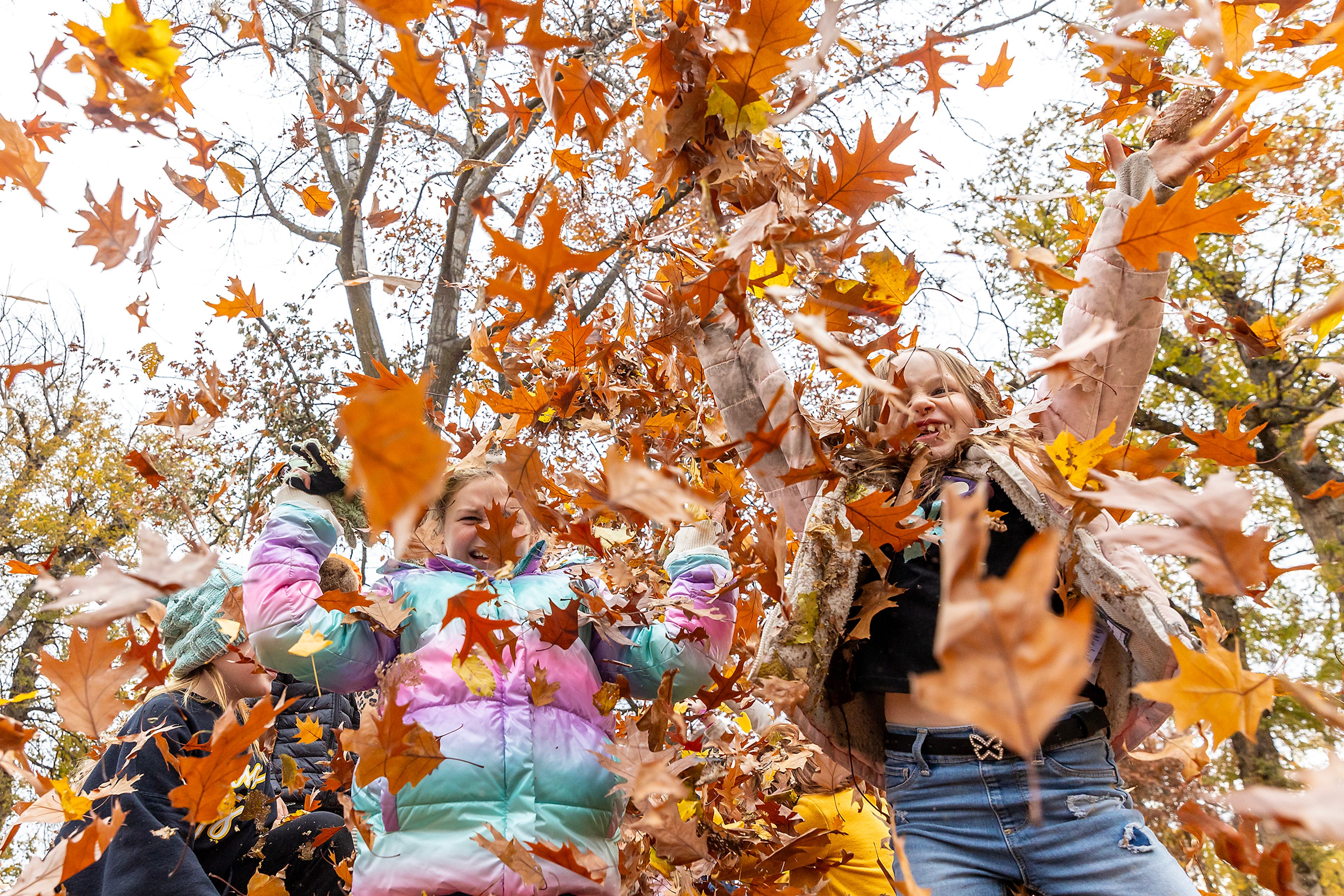 Alyvia Brower, left, and Paxley Jensen are surrounded by falling leaves outside Children's House Montessori School at Pioneer Park Wednesday in Lewiston.