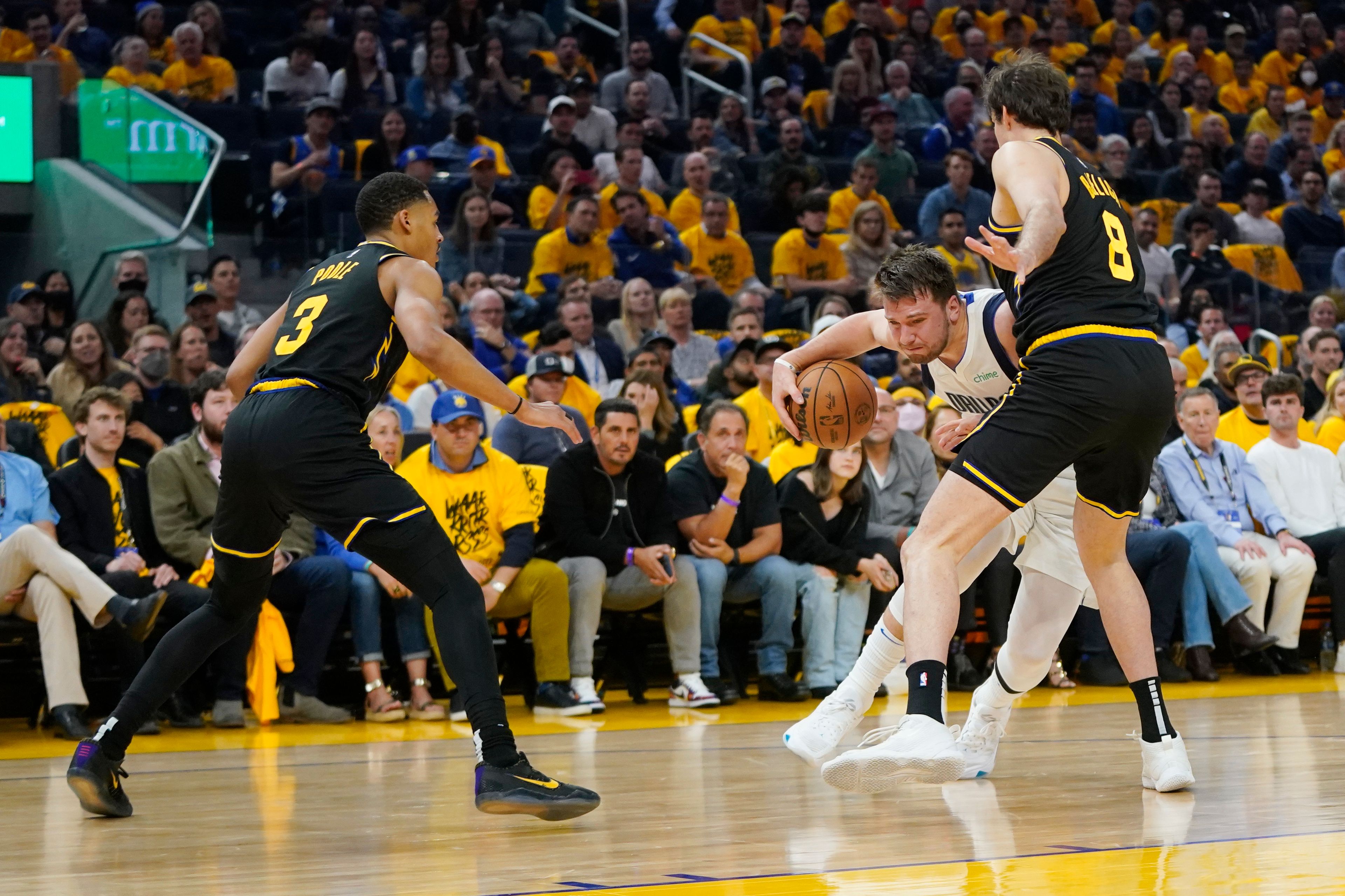 Dallas Mavericks guard Luka Doncic, center, dribbles between Golden State Warriors forward Nemanja Bjelica (8) and guard Jordan Poole (3) during the first half in Game 5 of the NBA basketball playoffs Western Conference finals in San Francisco, Thursday, May 26, 2022. (AP Photo/Jeff Chiu)