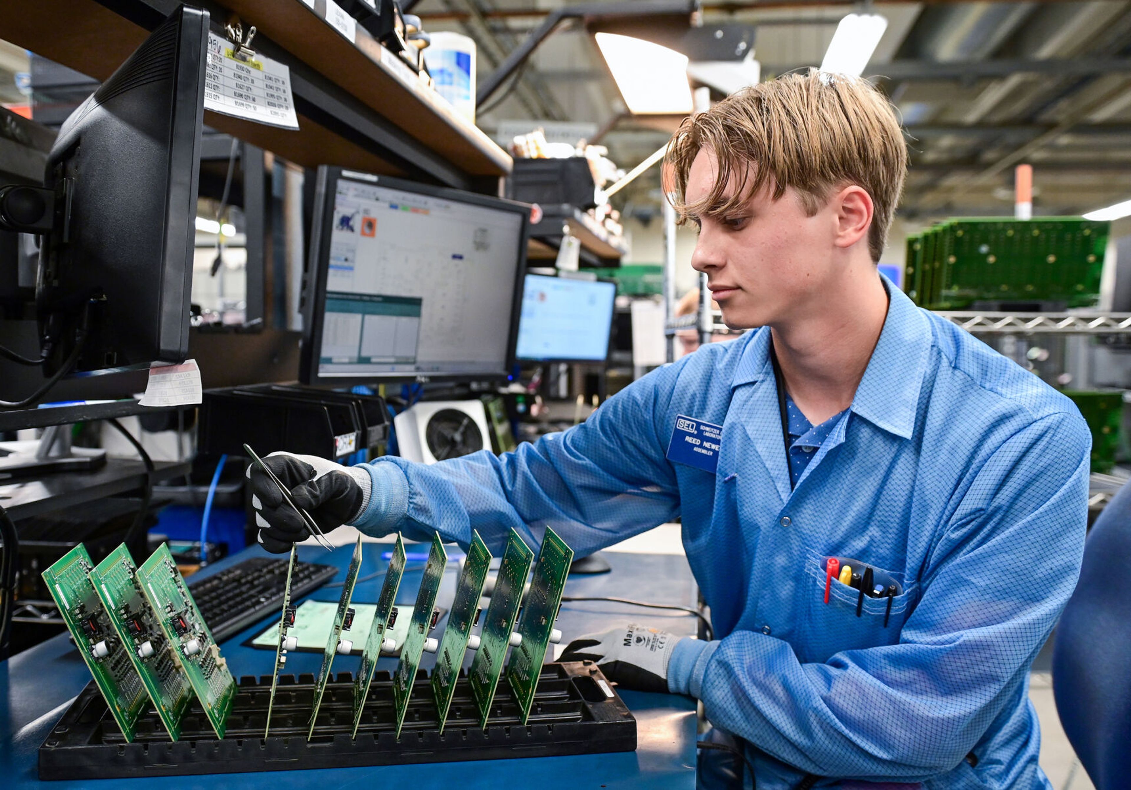 Reed Newell, a Pullman High School senior and member of the Summer Assembler Program, places stickers to prepare circuit boards for further processing at Schweitzer Engineering Laboratories on Thursday in Pullman.