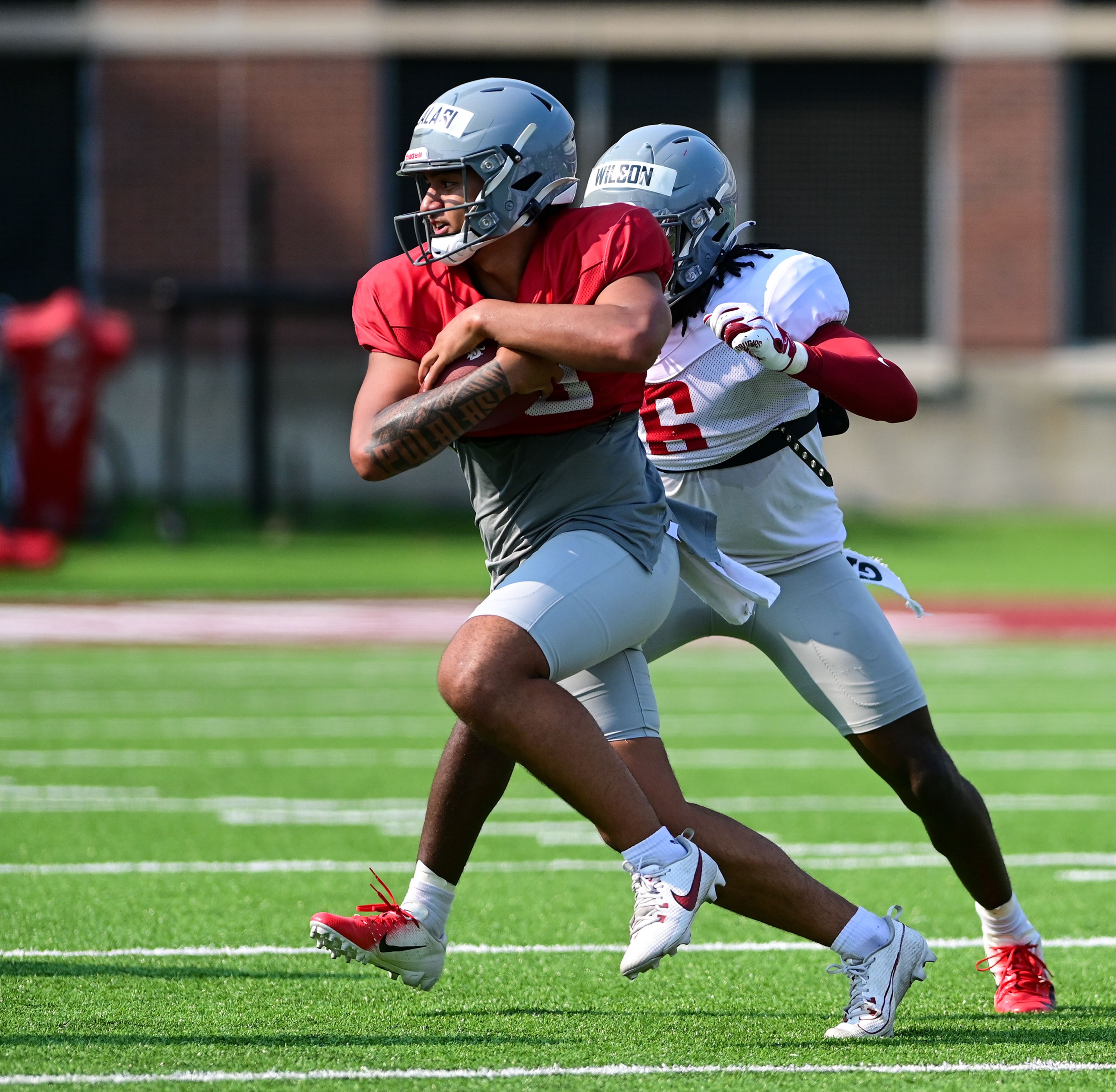 Washington State running back Leo Pulalasi carries the pass past defensive back Adrian Wilson during WSU’s fall camp on Friday in Pullman.