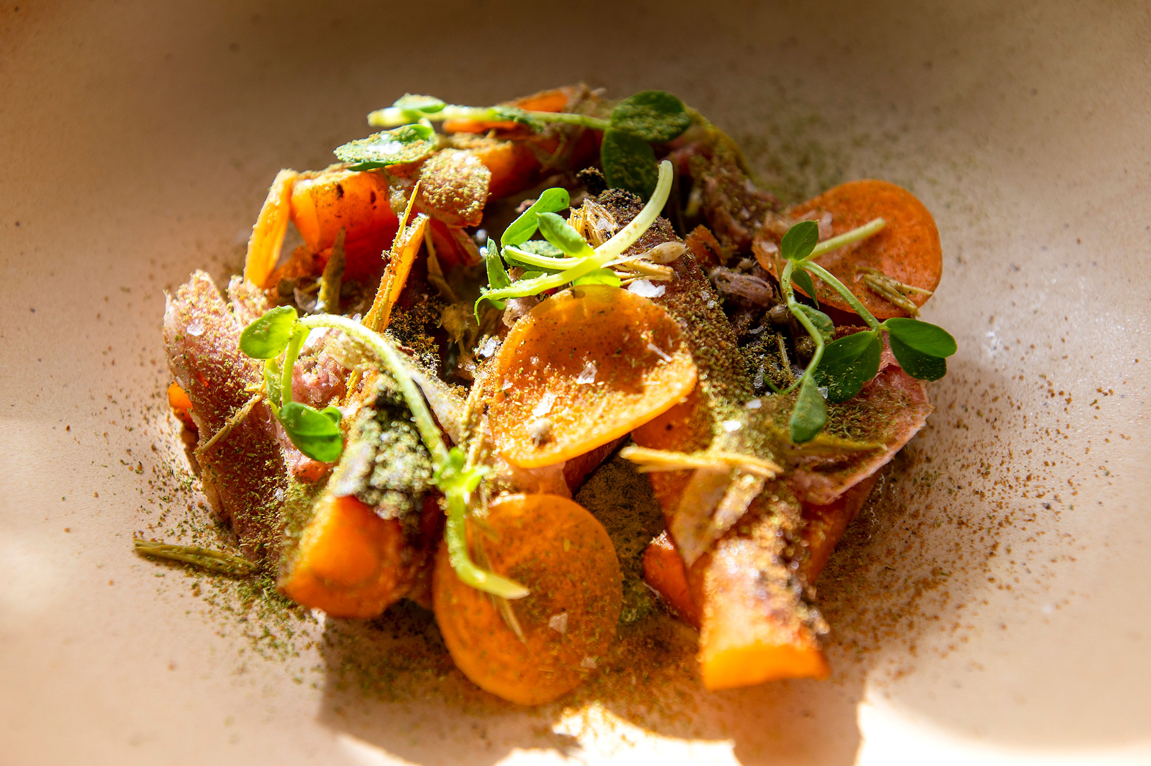 A warm salad of beef fat-roasted Ronnigers farms carrots and Texas Ridge bacon with Wingover pea shoots, Brush Creek Creamery feta and preserved wild chives foraged last spring made by chef Ian Pecoraro is seen here. Pecoraro said this is a typical dish one might expect in their subscription to Cellar Door Cooking.