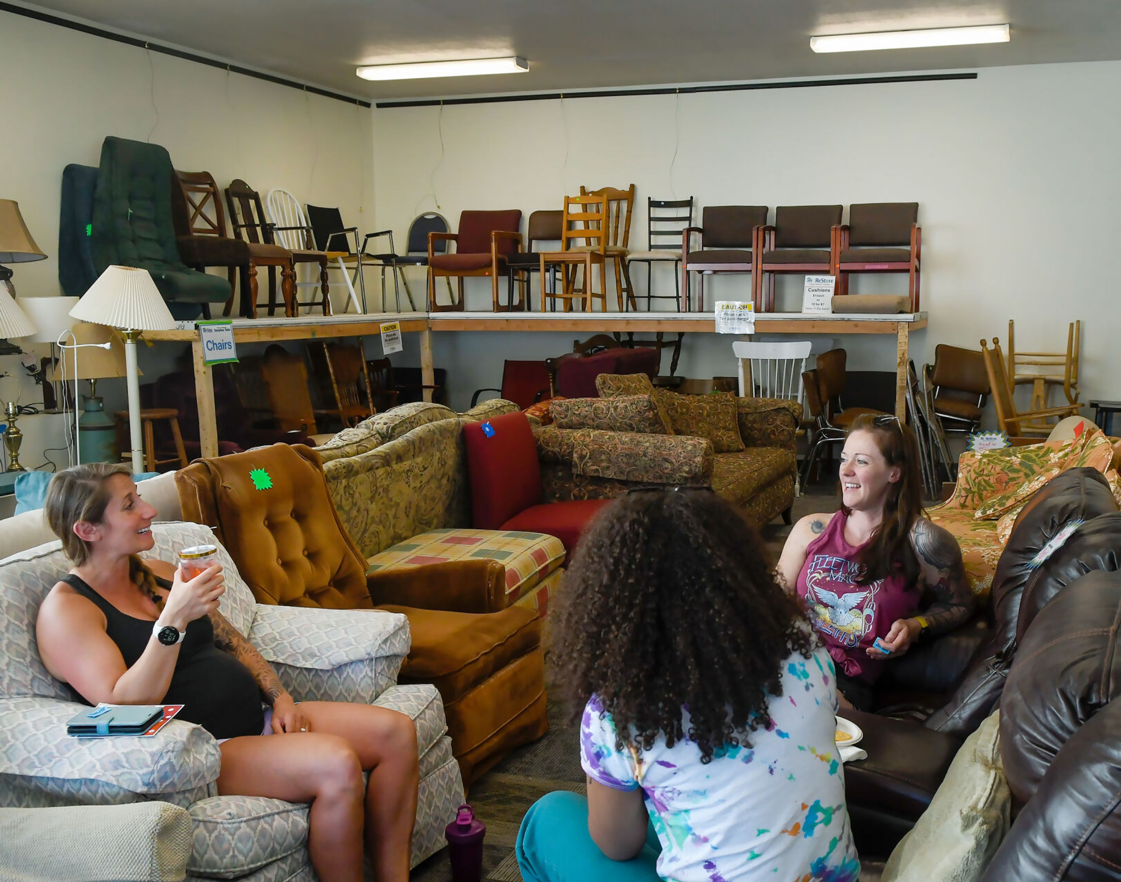 Tia Taylor, left, Amara Bailey, center, and Andie Severson, right, talk in the furniture section of the Palouse Habitat for Humanity ReStore at the store’s grand reopening celebration in Moscow on Thursday.