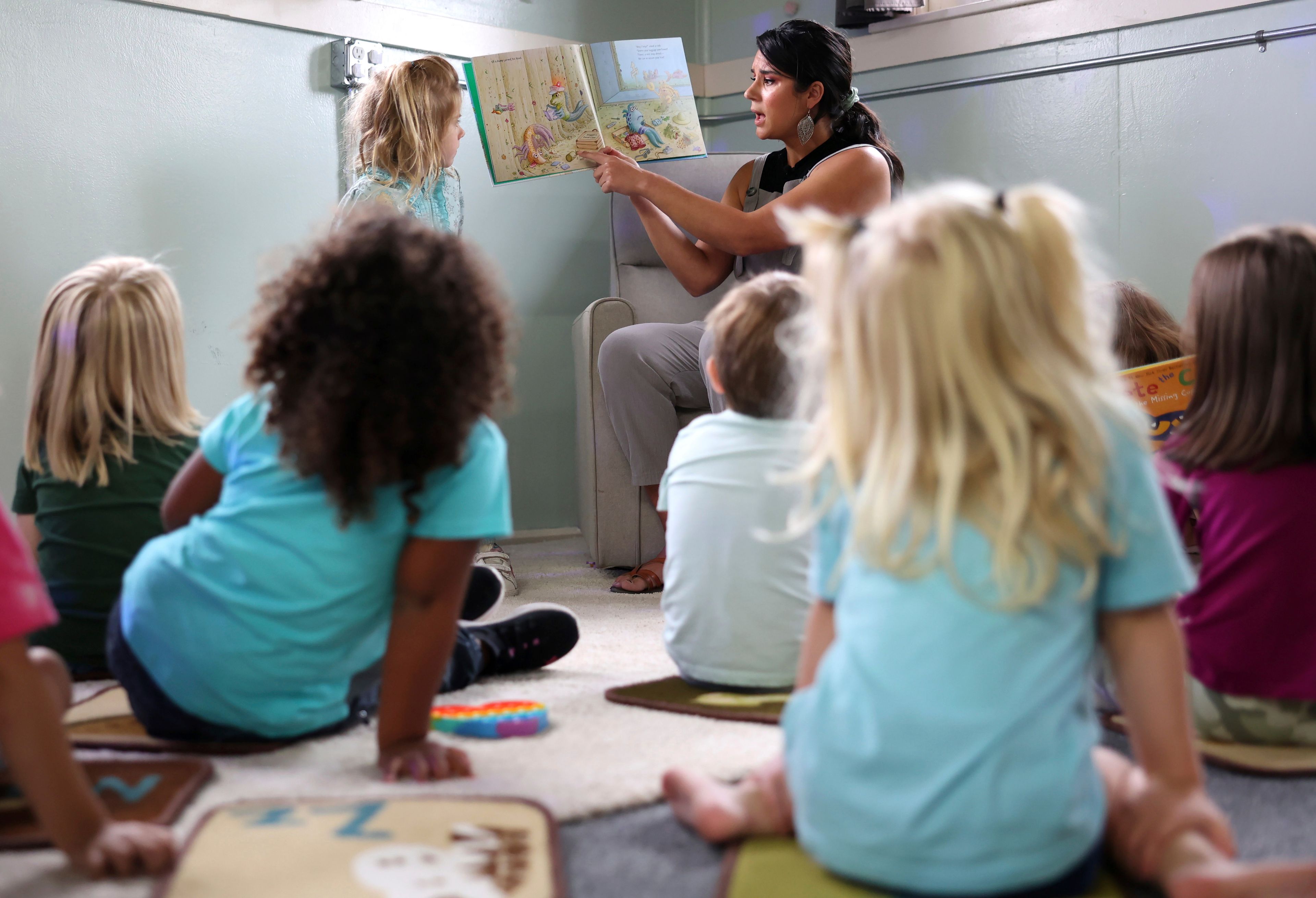 Kiera Holthusen reads a book at Bumble Art Studio day care center in Astoria, Ore., Friday, Sept. 2, 2022. From Oregon to New York, demand for child care far exceeds supply. Families are growing increasingly desperate as providers deal with staffing shortages exacerbated by the coronavirus pandemic as well as historically low pay worsened by inflation. (AP Photo/Craig Mitchelldyer)