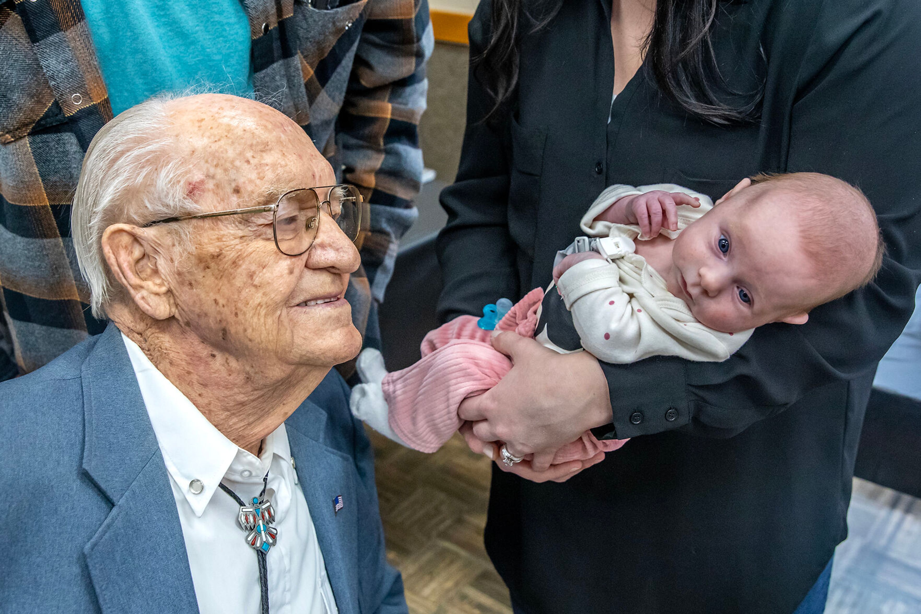 Floyd Thomason looks at his great great granddaughter Wrenlee Funke, 2 months, during his 100th birthday party Saturday at the Lewiston Community Center.