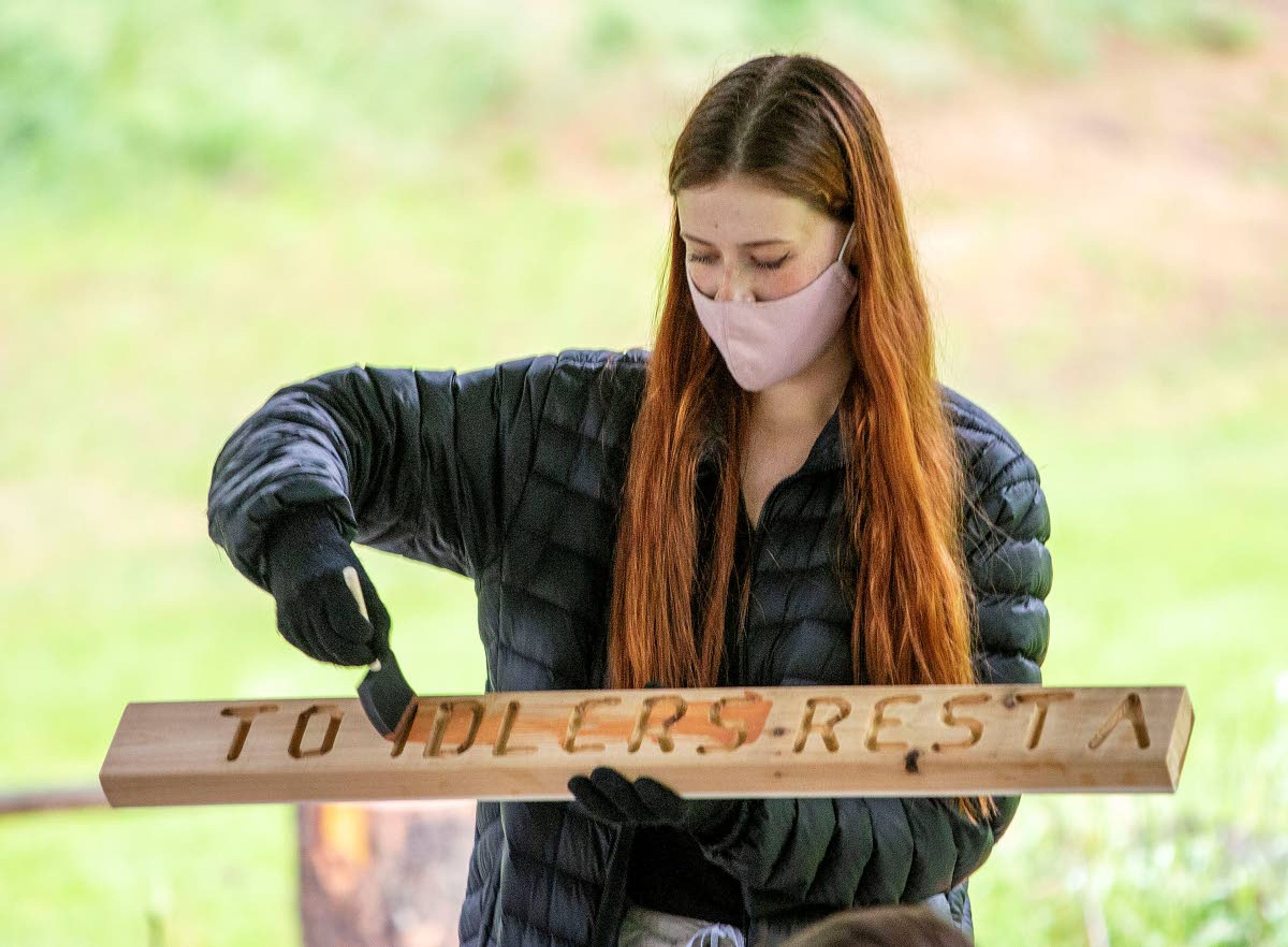 Aila Carr-Chellman demonstrates how to stain a wooden sign.