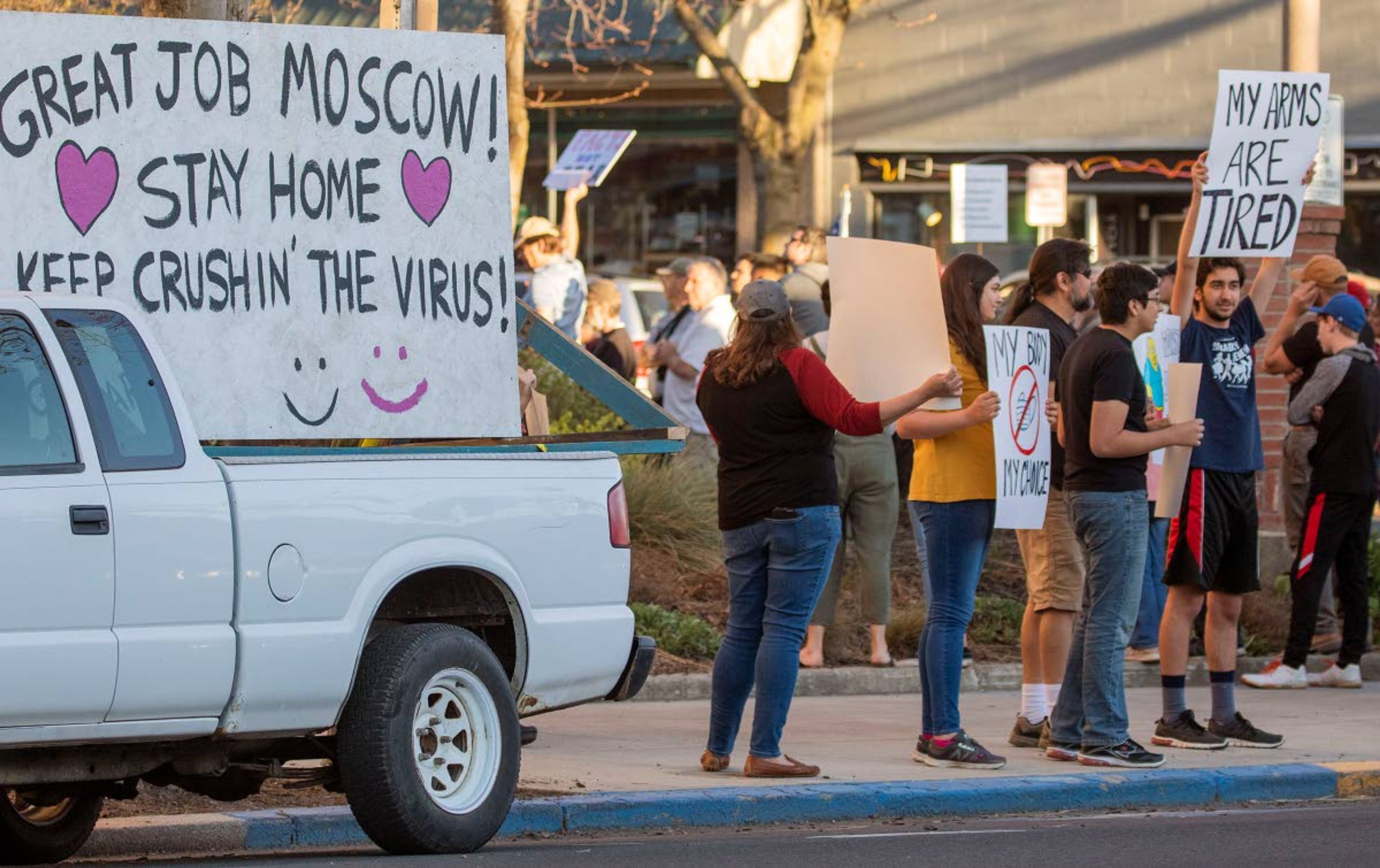 A sign in a counter-protester's truck stands next to the Liberate Moscow Peaceful Protest on Monday outside Moscow City Hall. The protesters were urging city leaders to reverse an order that closed businesses and asked people to stay at home to help prevent the spread of the new coronavirus.