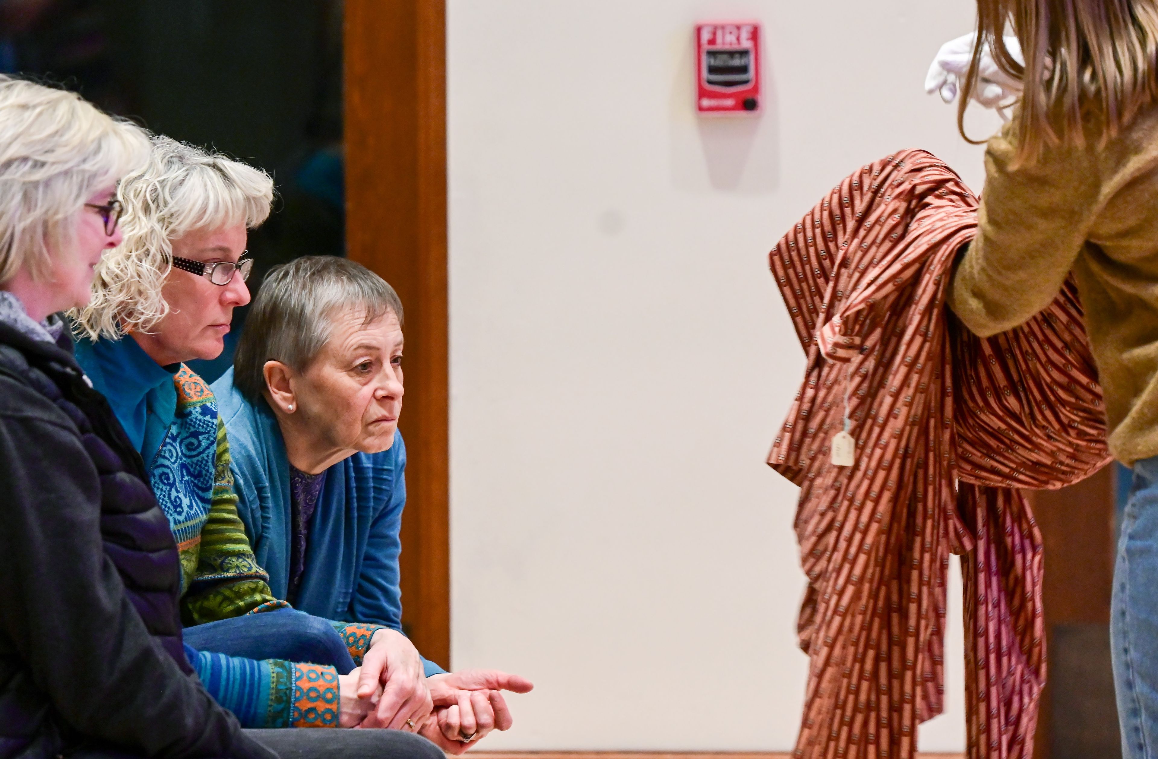 Sara Lawrence, from left, Julie Trail and Chris Schultz take a closer look at a dress from the Leila Old Historic Costume Collection being held by Cameron Nielson, right, a first-year masters student in costume construction at the University of Idaho, during a presentation by collection curator and UI professor Sonya Meyers at the 1912 Center in Moscow on Tuesday.