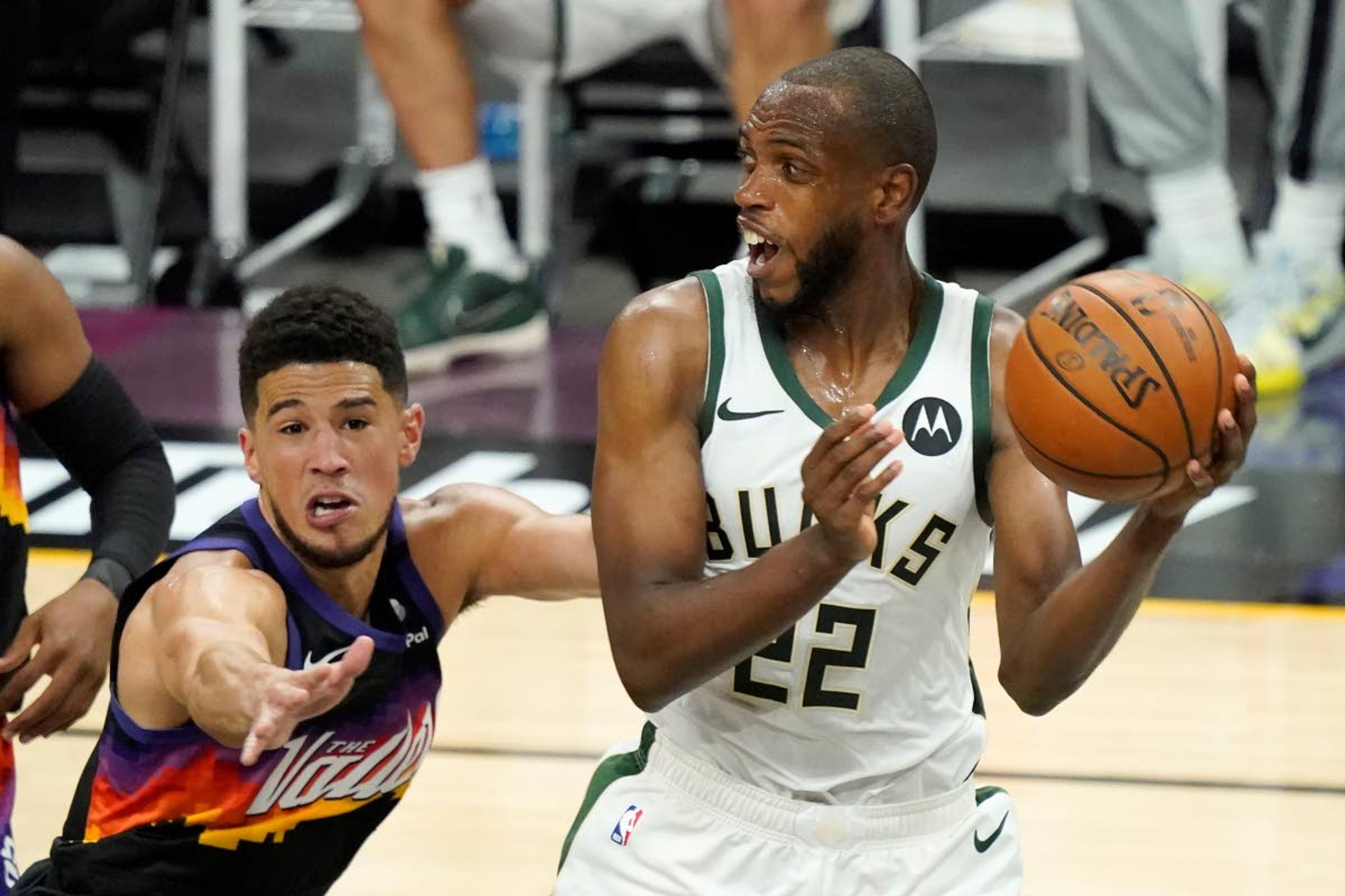 Milwaukee Bucks forward Khris Middleton (22) is defended by Phoenix Suns guard Devin Booker during the second half of Game 2 of basketball's NBA Finals, Thursday, July 8, 2021, in Phoenix. (AP Photo/Matt York)